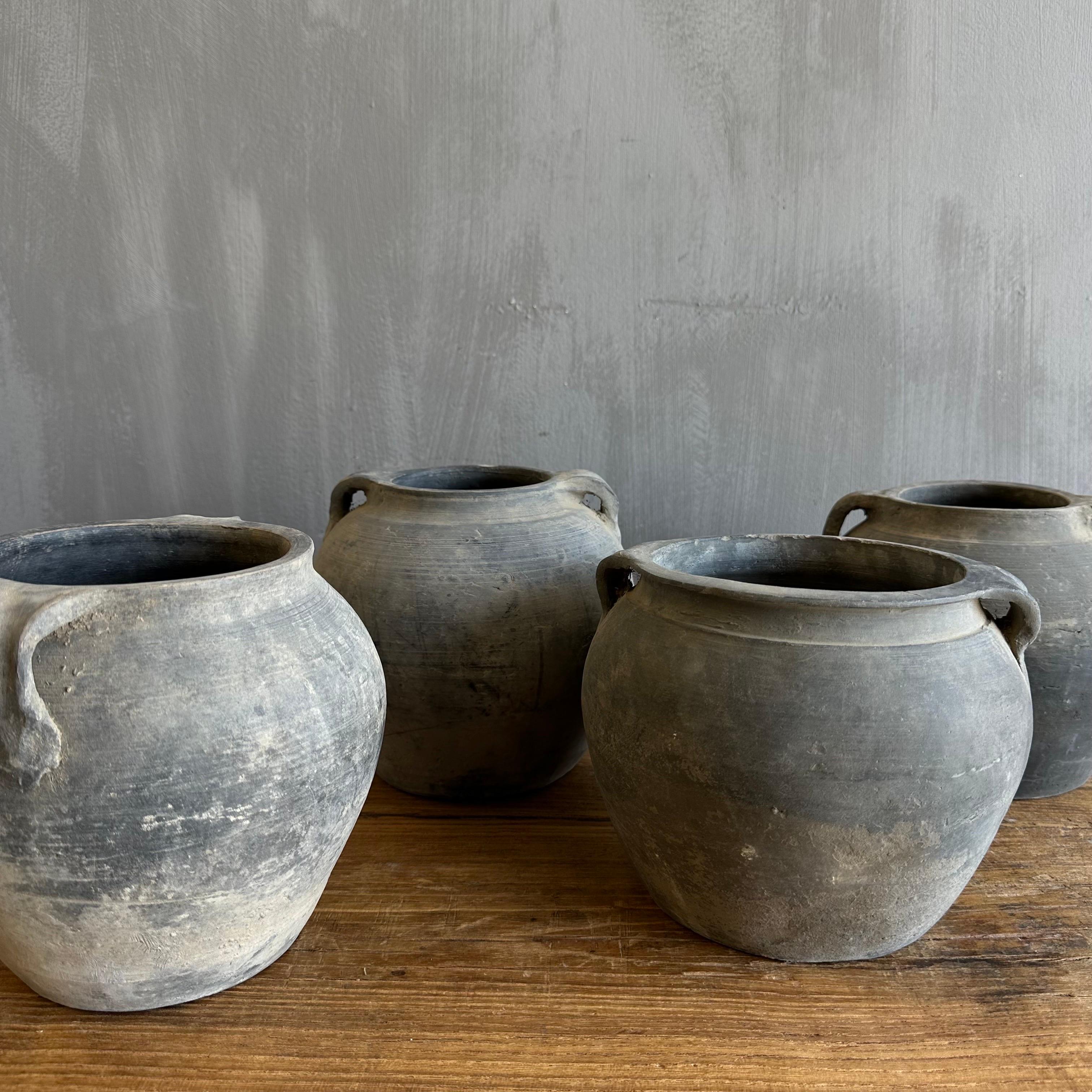 Beautiful weathered 2 handled grey vintage clay pot that is beautifully colored and authentically worn. The surface of the pot and handle are peeling in places, revealing the original clay below. 

These qualities give the pot a lived-in appearance
