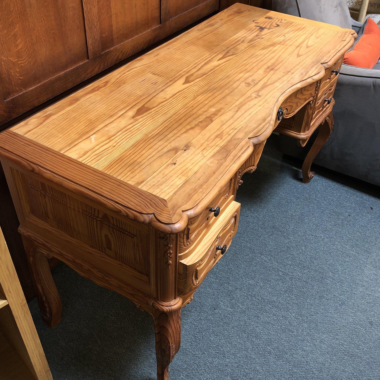 A vintage style writing desk. Crafted of natural pine, this charmer struts sinuous curving legs and curves, along with plenty of useful storage.