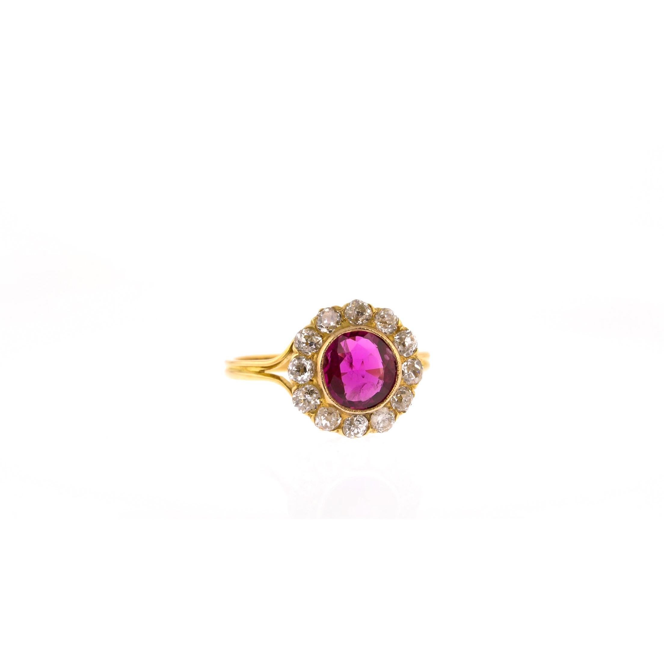 This vibrant yellow gold ring will add colour to any occasion. At its centre is a beautiful oval ruby with red overtones and deep, pink-purple undertones. Its warmth is complemented by 12 round diamonds, arranged around the ruby in a pretty vintage