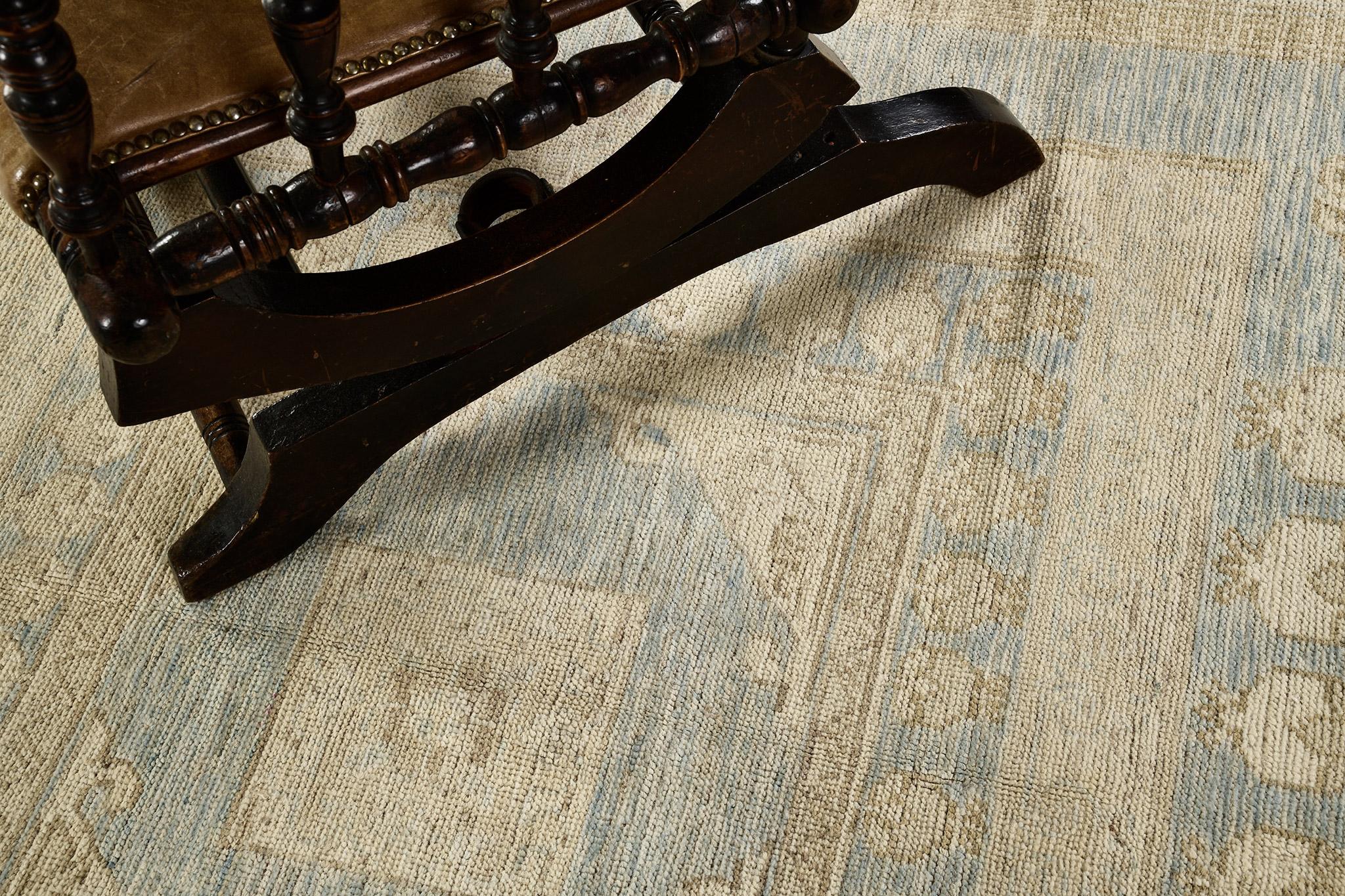 A phenomenal Oushak design revival rug that has a classic and timeless pattern. Featuring the collaboration of muted tones of dusty blue, sky blue and sand, this classy rug is composed with enchanting graceful palmettes and florid elements that