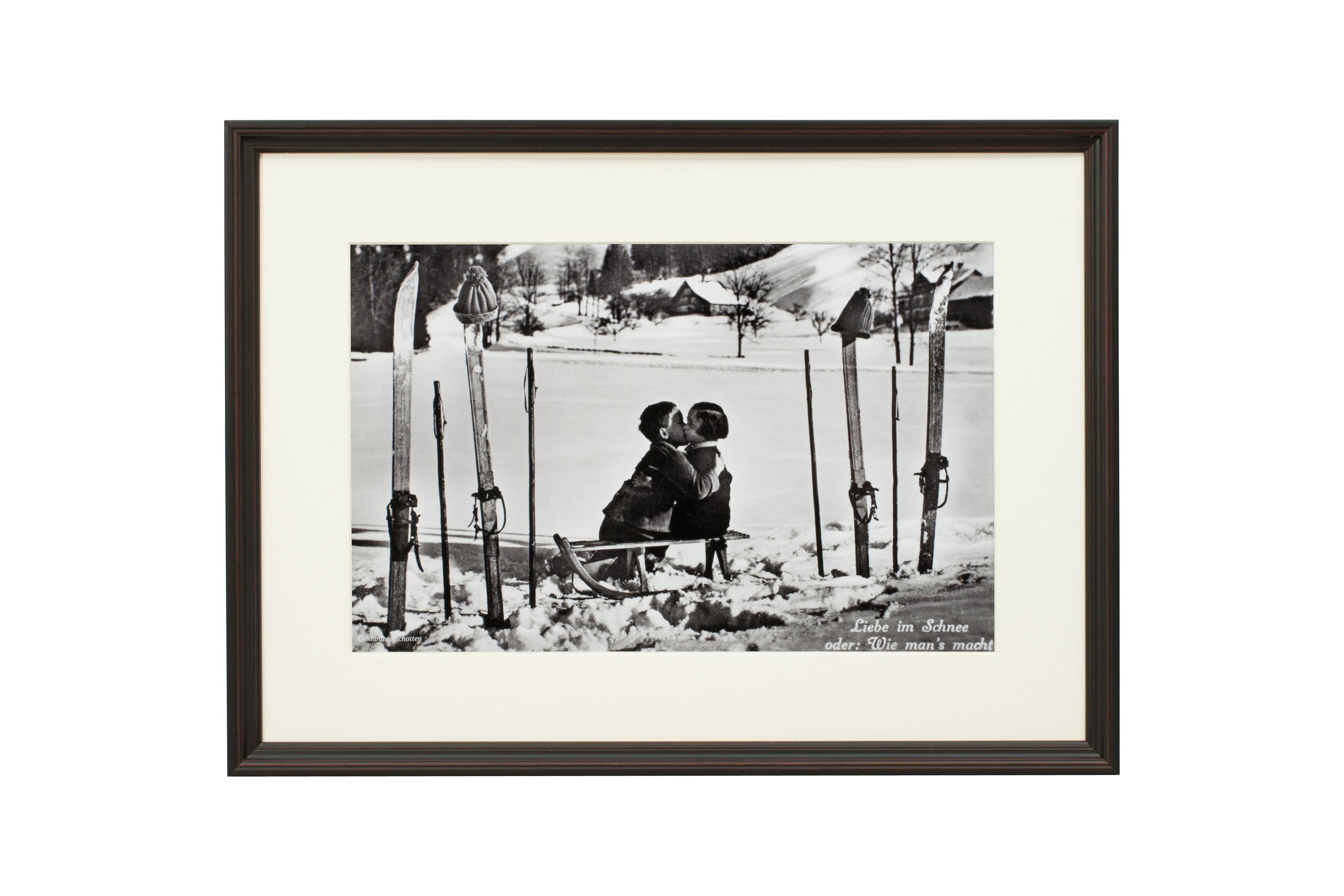 'LIEBE IM SCHNEE', a modern framed and mounted black and white photograph after an original 1930's skiing photograph. The frame is black with a burgundy undercoat, the glazing is clarity+ premium synthetic glass. Black & white alpine photos are the