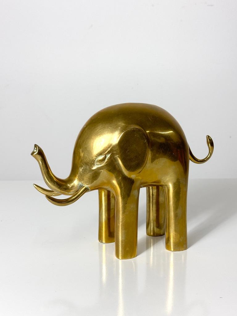 A golden elephant sculpture by Dolbi Cashier circa 1980

Modernist style elephant in brass with trunk raised as a symbol of good fortune
Label intact to underside

10 inch width
3.5 inch depth
8 inch height