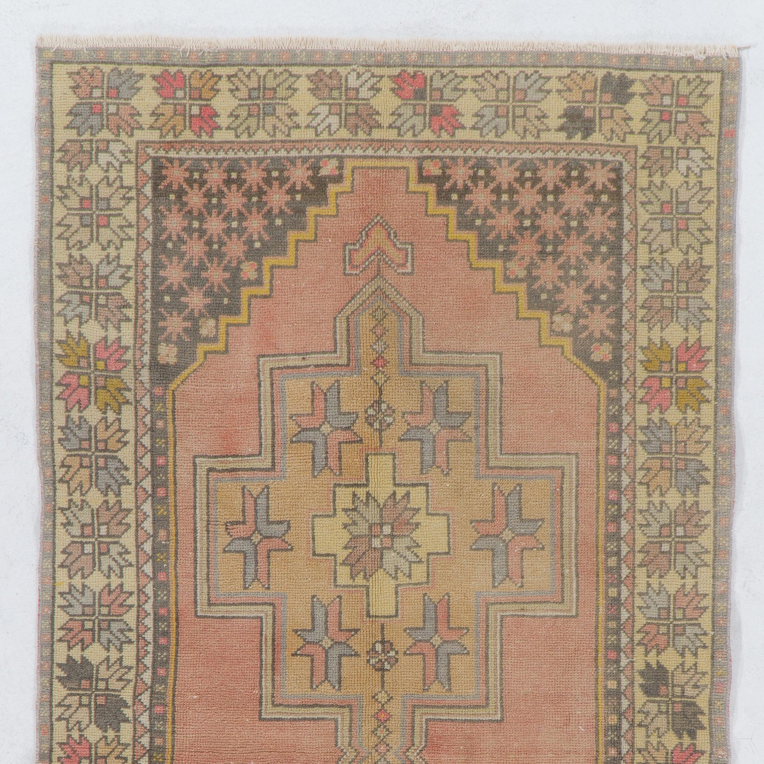 Esta alfombra vintage de Anatolia Central presenta dos medallones enlazados en suaves tonos tostados y dorados y motivos en forma de cruz en el interior sobre un campo liso en suave rojo apagado. Los esquineros en gris marengo están decorados con