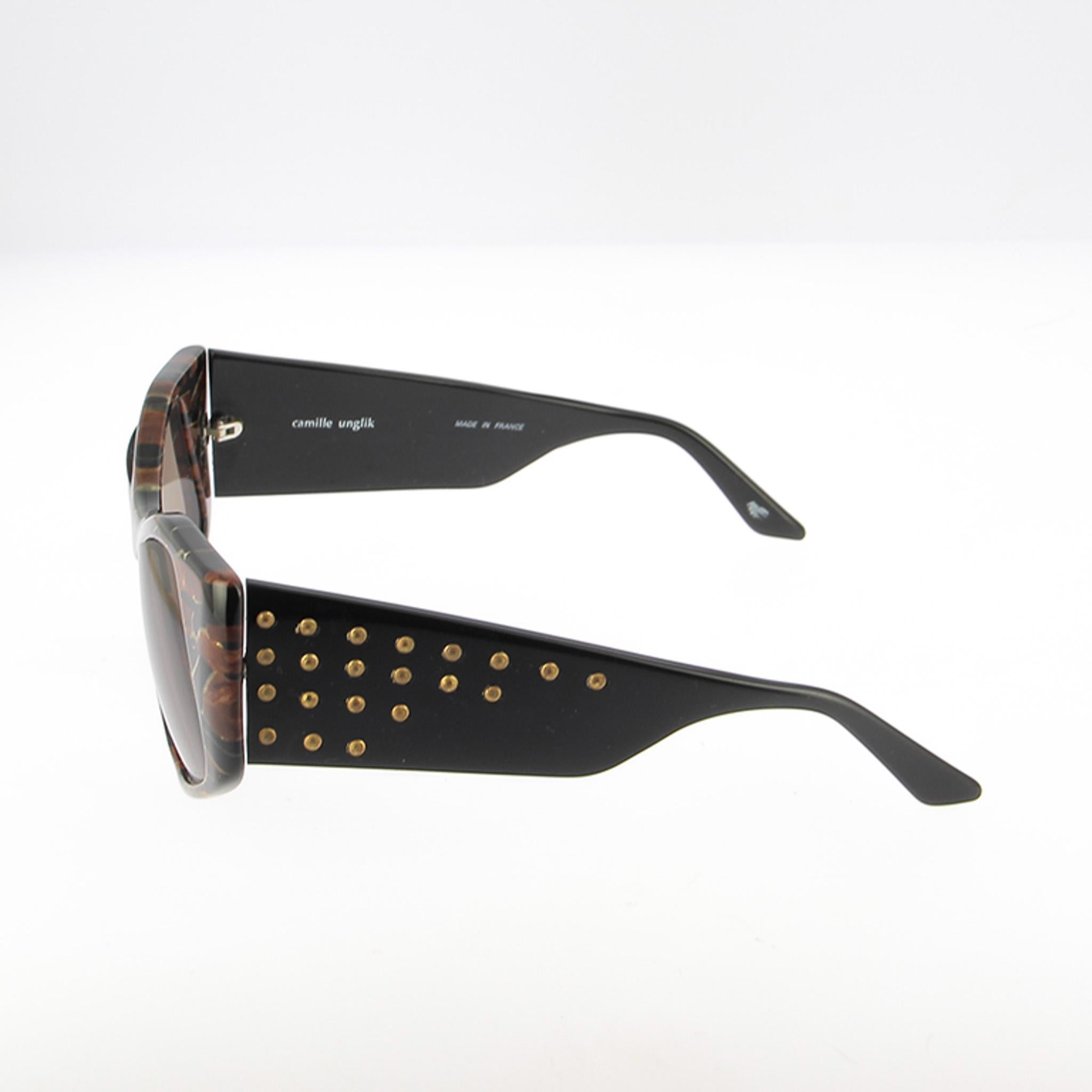 Immergiti nell'eleganza senza tempo degli anni '80 con questi splendidi occhiali da sole vintage di Camille Unglick, un'icona dell'epoca.
Realizzata in acetato di prima qualità, la montatura presenta una silhouette oversize a occhi di gatto che