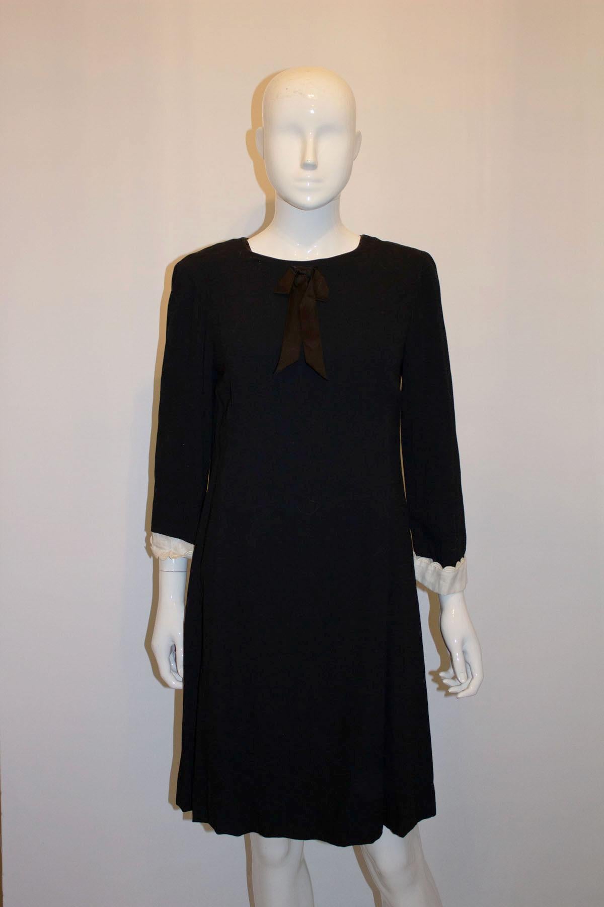 A chic black vintage dress by Susan Small.  The dress has attractive tucks on the front, a central back zip and is fully lined. It has white cuffs on the sleave and satin bow detail.
Measurements: Bust up to 36'', length 37''