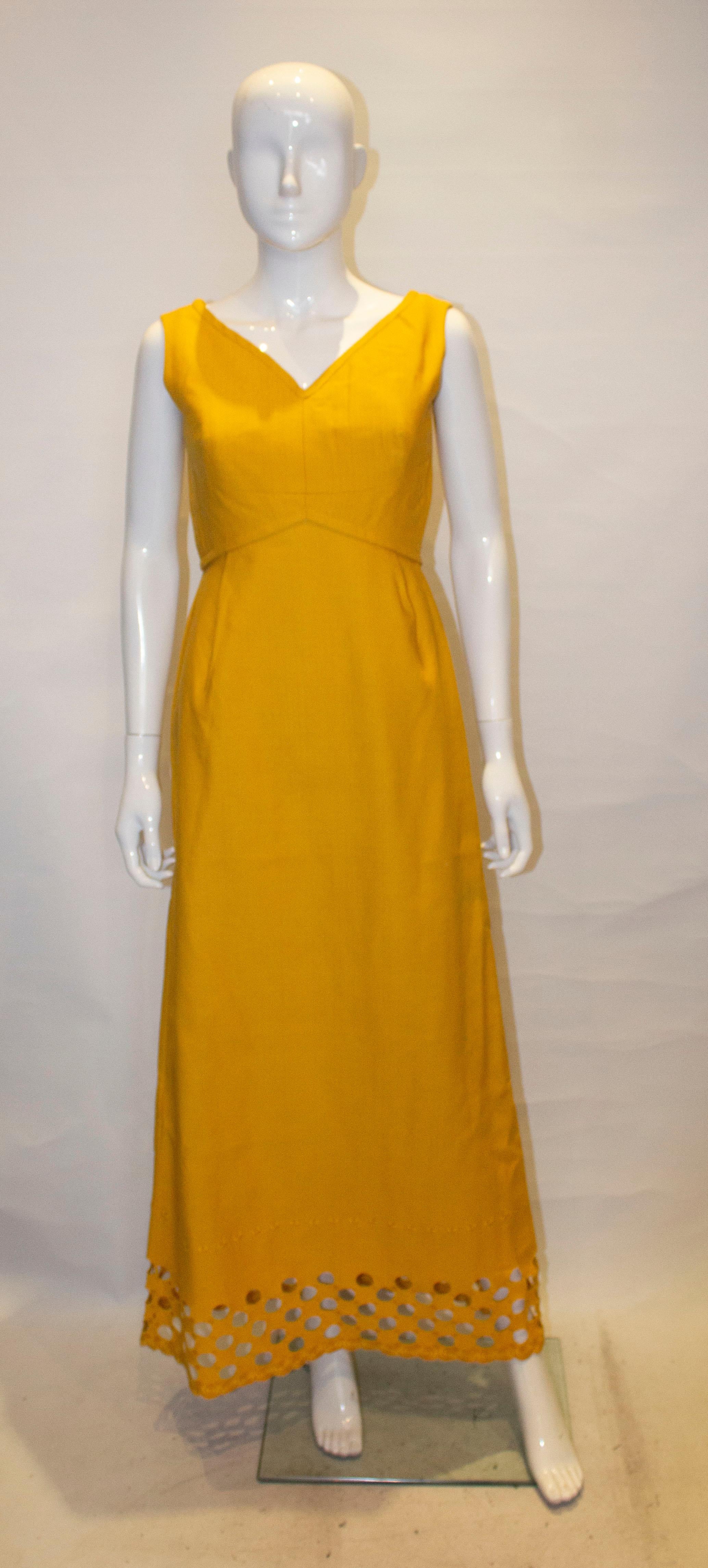 A chic vintge evening dress by Susan Small. In an attractive soft gold/mustard colour, the dress has a v neckline and backline with cut out and embroidery detail at the hem. It is fully lined.