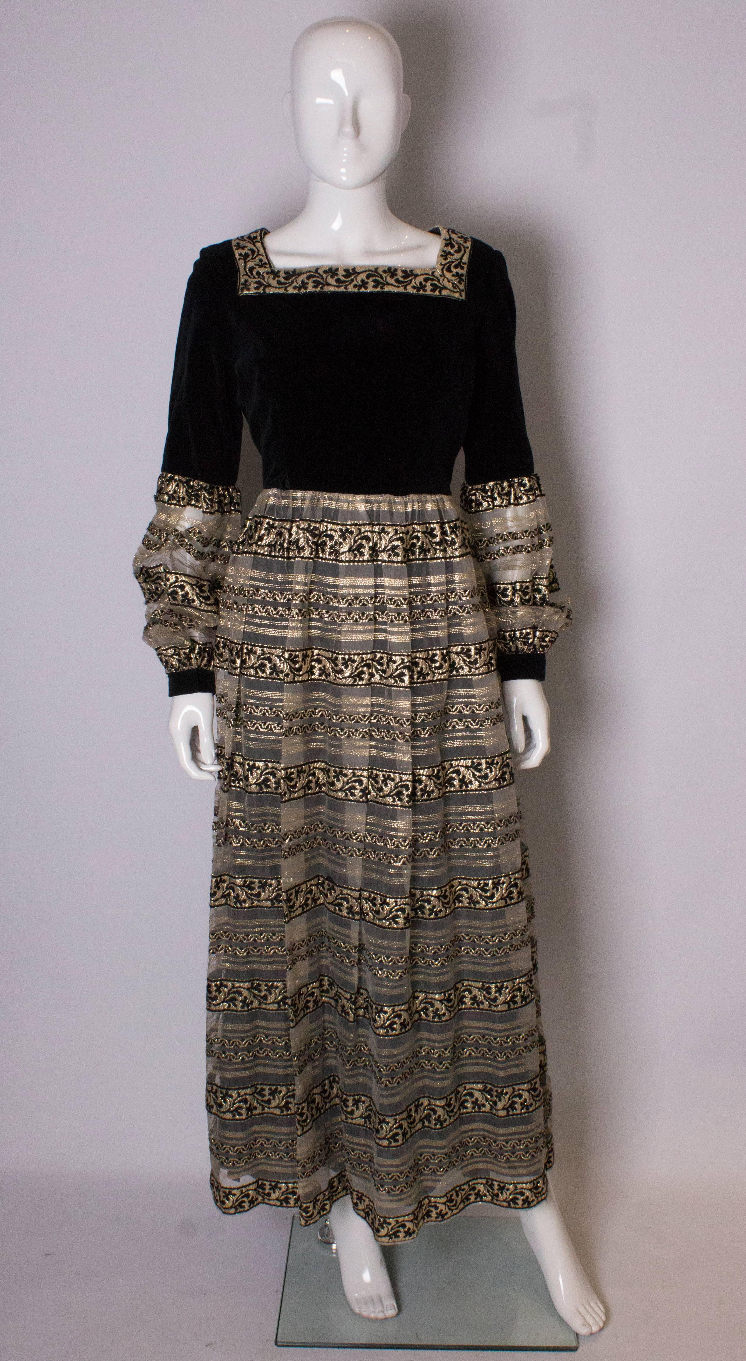 A chic gown by Susan Small.  The dress has a black velvet upper body and upper sleeves, with a gold and black skirt and lower sleeves.