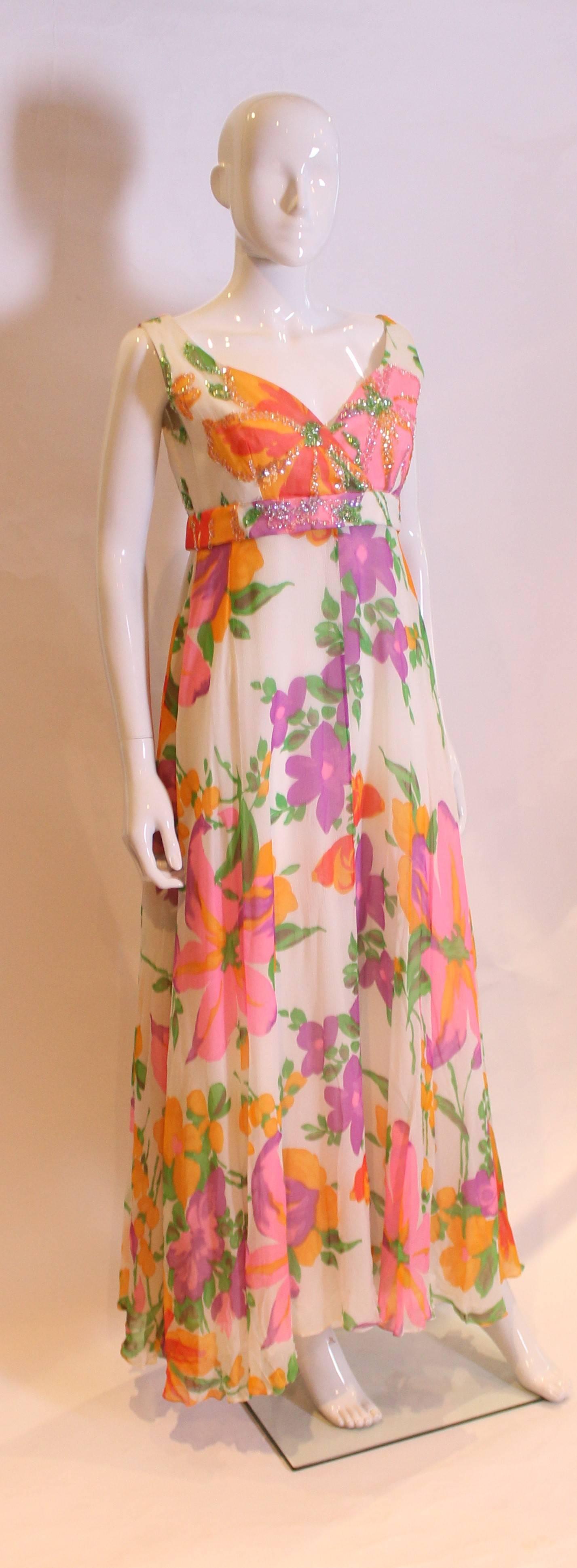 A great Summer party gown by British designer Susan Small. The gown is in a colourful mix of tropical colours, pink, purple, green and orange. It has a crossover v neckline, band under the bust, flared skirt and a central back zip.