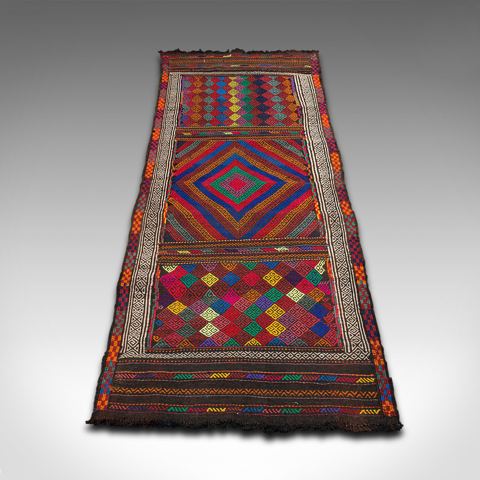 This is a colourful vintage Suzani Kilim runner. A Middle Eastern, woven hallway or entrance hall carpet, dating to the late 20th century, circa 1980.

Of useful entrance hall or bay window size at 79cm x 211cm (31