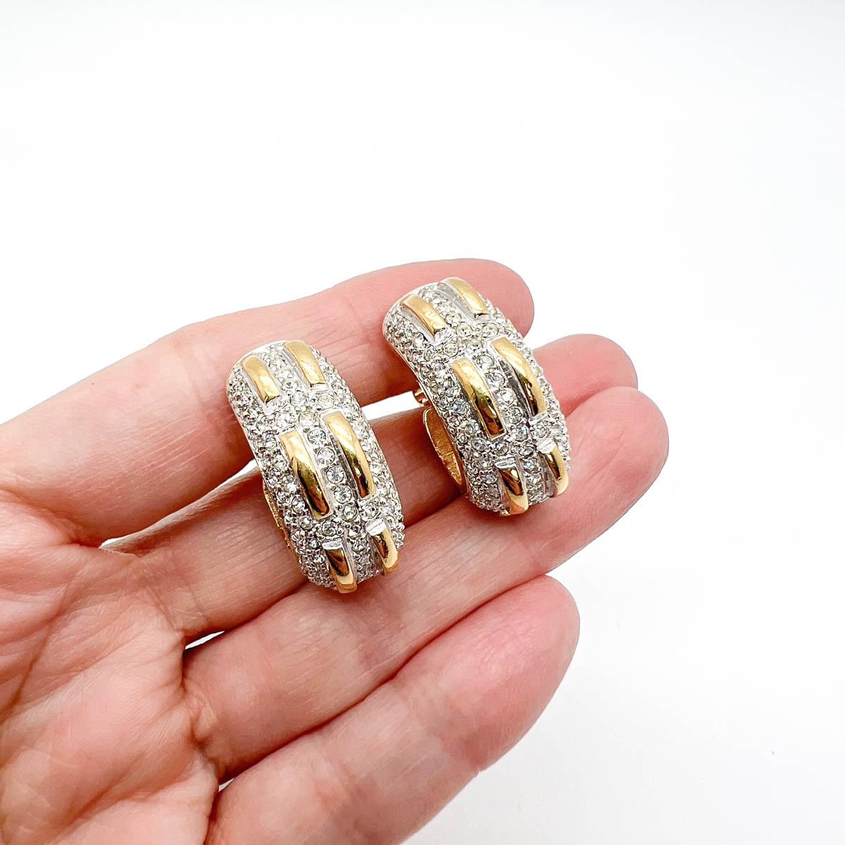 A gorgeous pair of Vintage Swarovski Huggie Earrings. The uber glam and wearable huggie hoop is embellished with pave set crystals and golden tracks. The gold and silver mix proving a perfect style statement. One that you will want to wear and wear
