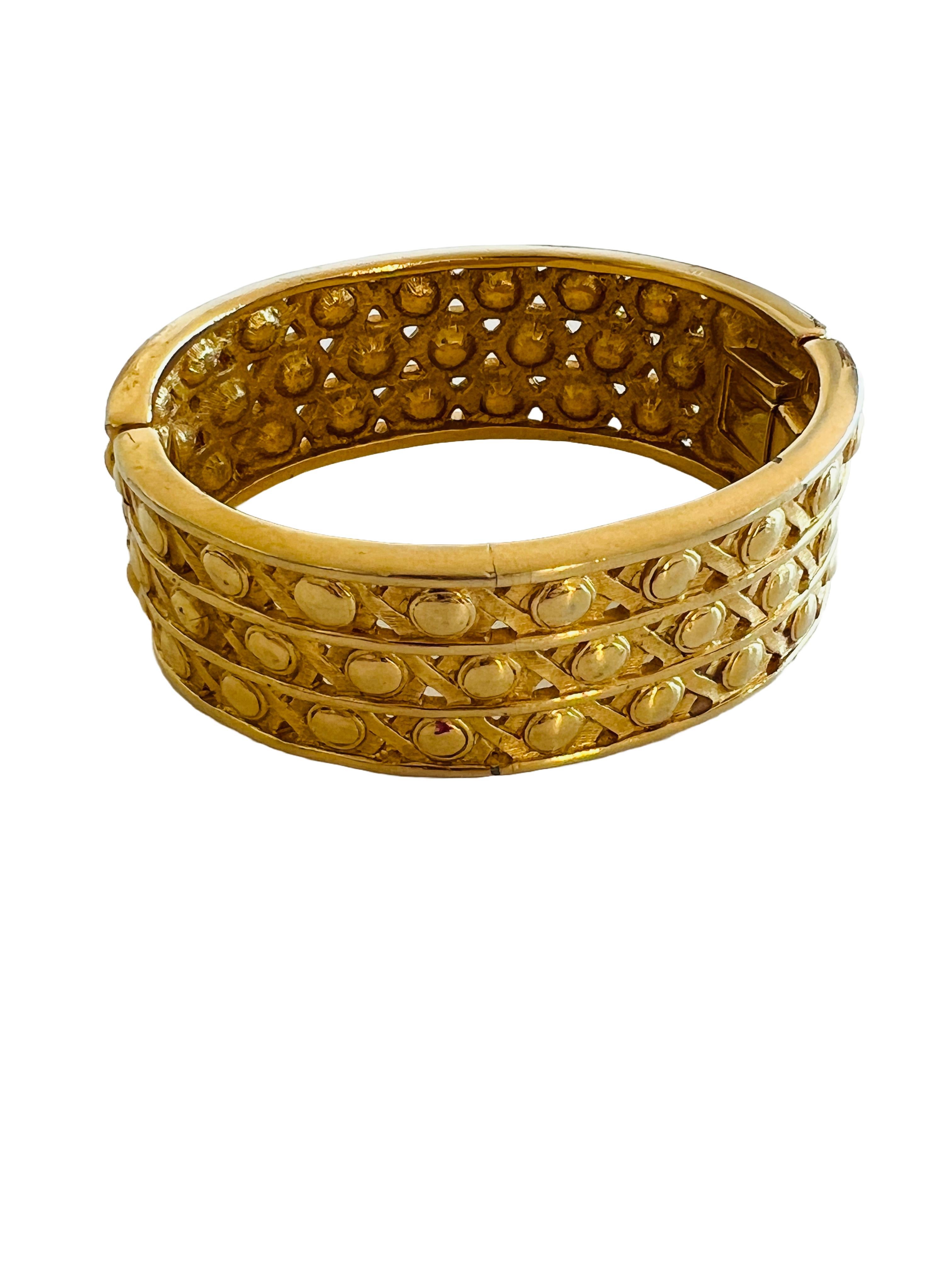 Dieses Vintage-Armband mit Scharnier von Swarovski besteht aus einem goldfarbenen Metallband, das mit klaren Strasssteinen verziert ist. Das Design des Armbands besteht aus drei Reihen von Strasssteinen, die in einem rautenförmigen Gittermuster