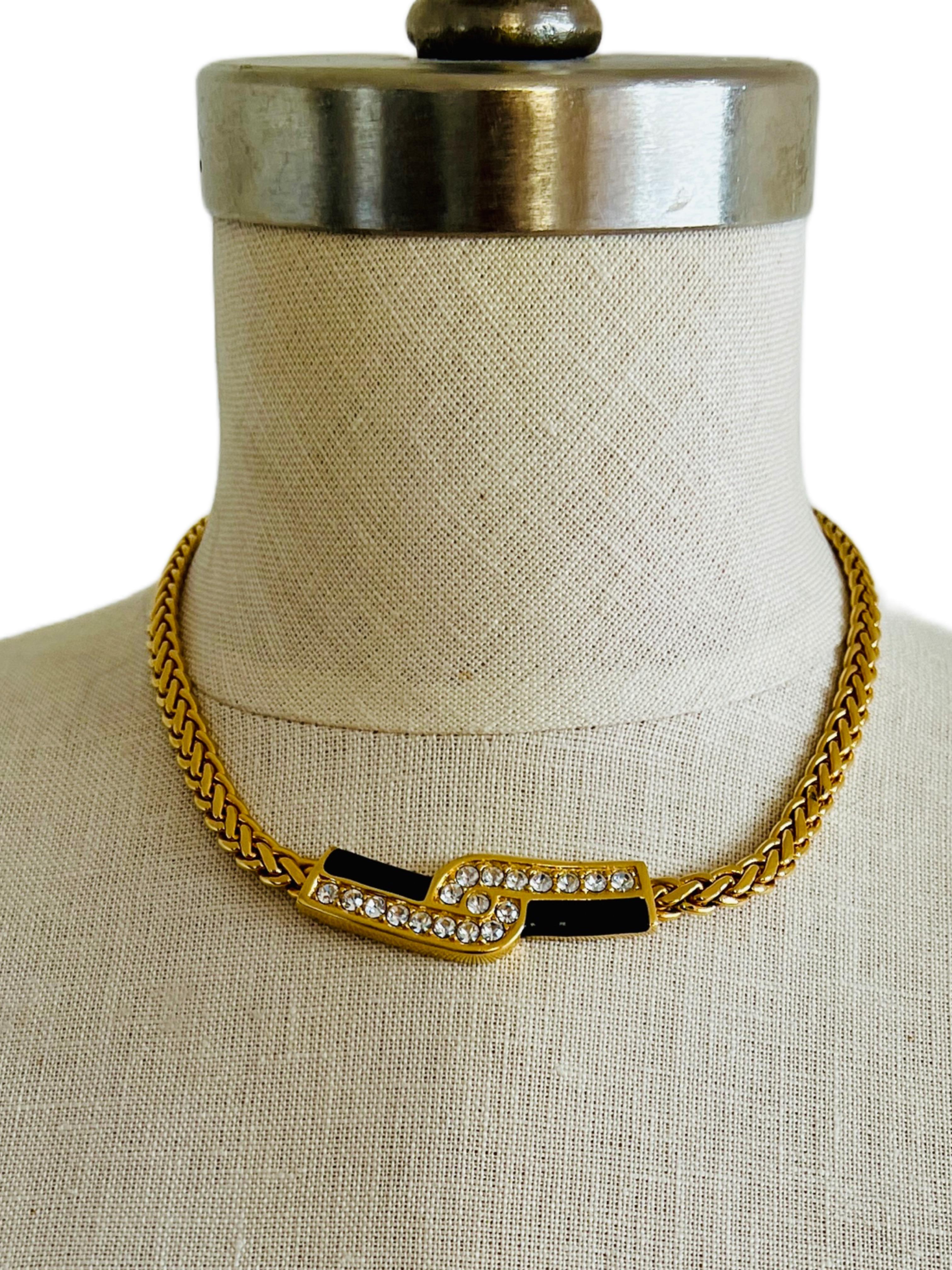 Add a touch of glamour to your outfit with this vintage Swarovski choker necklace from the 1980s. The necklace features a black enamel and gold pavé rhinestone bar pendant on a gold plated flattened wheat Spiga chain. This statement choker necklace