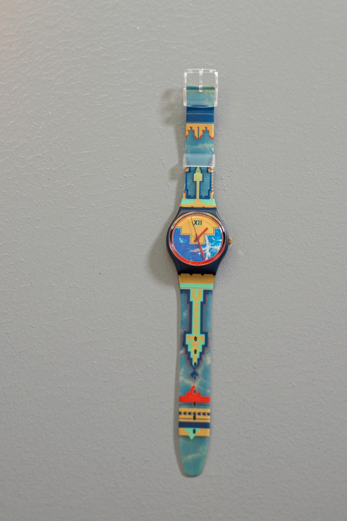 Eine alte Swatch mit einem wirklich einzigartigen Design. Das Armband hat eine Textur, die an Stammesmuster erinnert, die Farben dieser Uhr machen sie perfekt zu einem raffinierten oder sogar romantischen Outfit.

Material des Gehäuses: