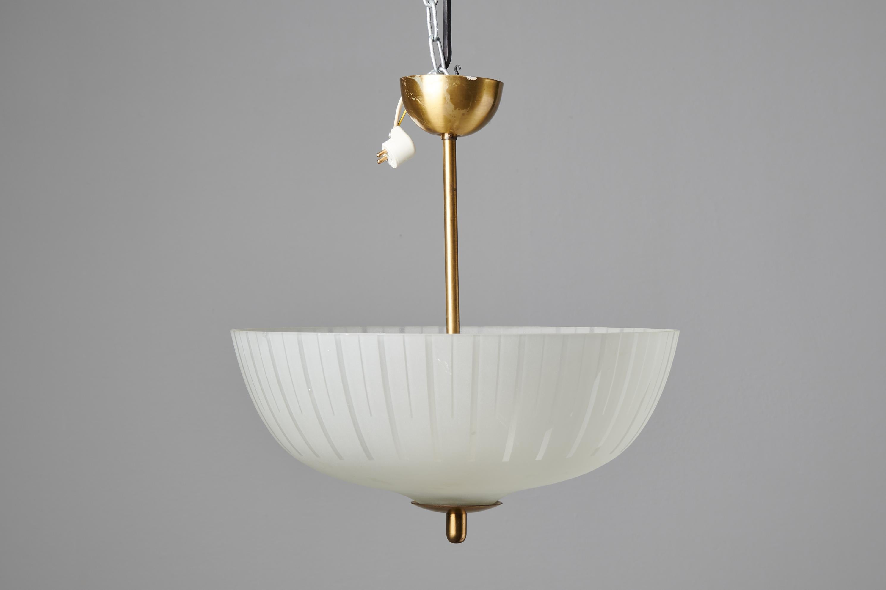Vintage Swedish ceiling light from around the 1940 with a cover in glass and suspension in brass. The light has three light sources and the glass cover has a subtle geometric design which filters the light nicely. The cover has a small insignificant