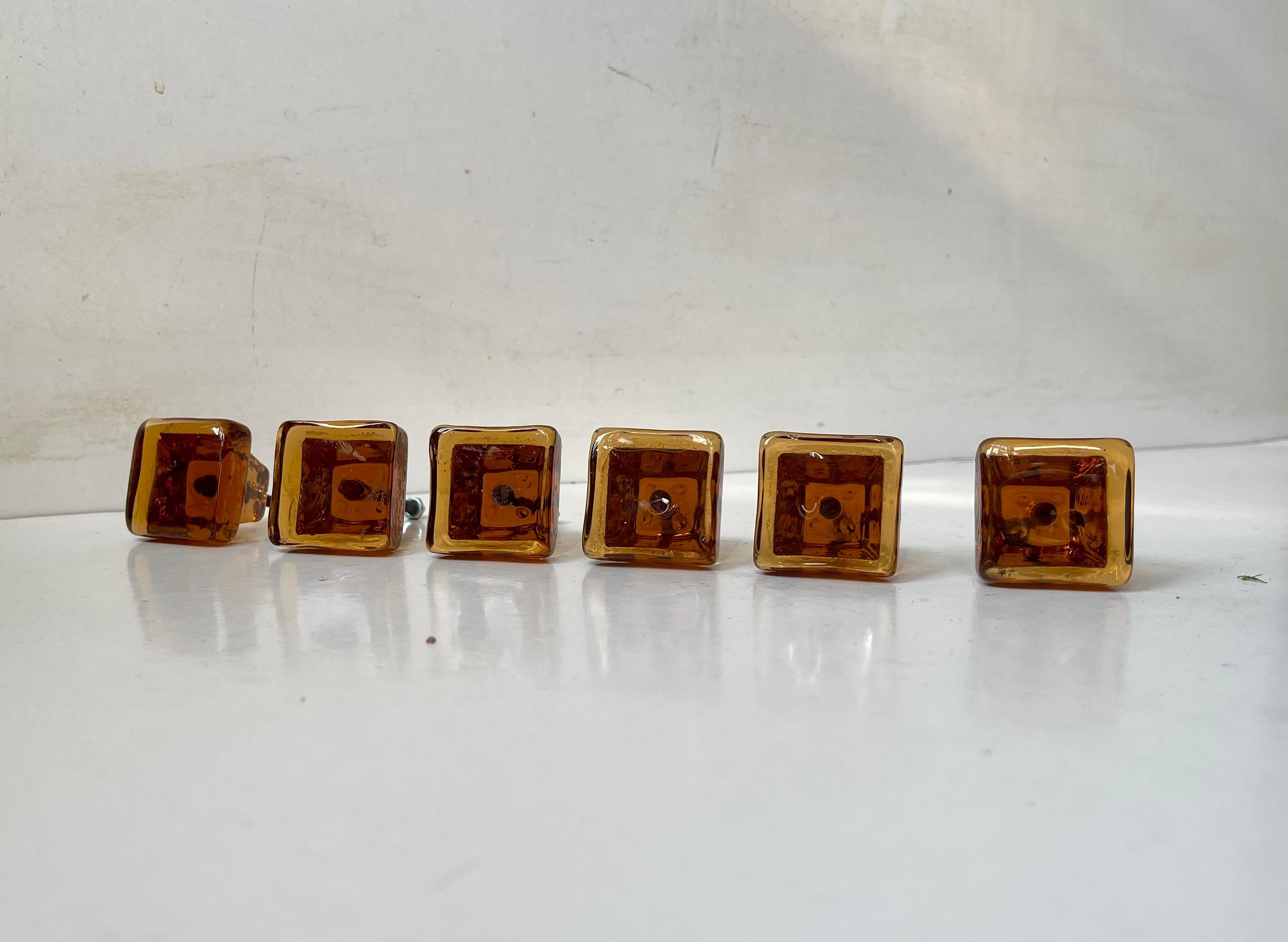 Ein seltener Satz von 6 bernsteinfarbenen/orangenen Tür-/Schubladenknöpfen aus Glas. In den 1960er Jahren in Schweden handgefertigt.   

Abmessungen: Taille: 7,5 cm, B/H: 3,8 cm.   

Der Preis gilt für das 6er-Set.