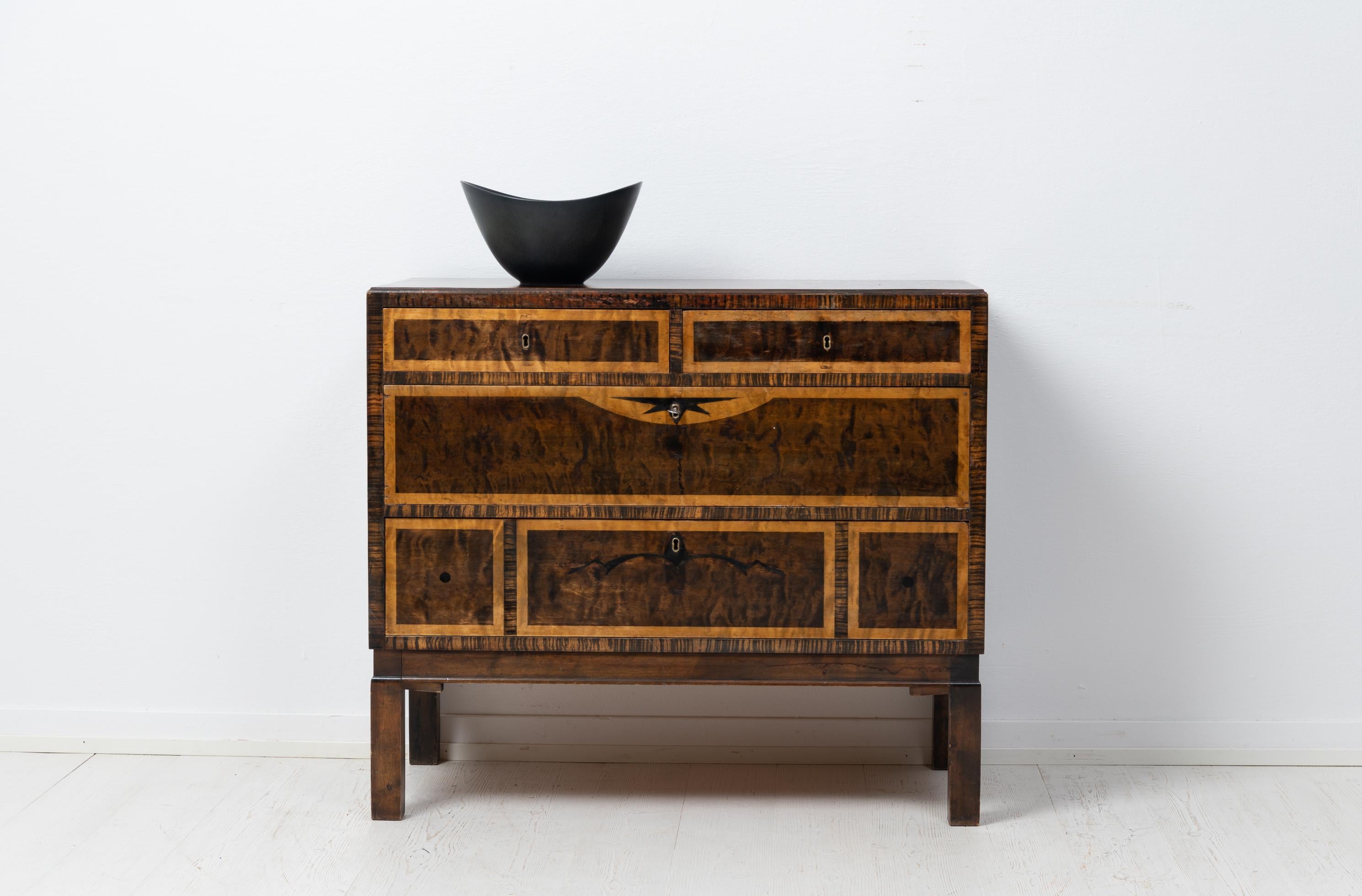 Swedish art deco commode or chest of drawers from the 1930s. The commode has 4 drawers and is veneered with multiple different kinds of wood, among those birch and zebrano, which creates a stunning geometric effect. The commode is in good vintage