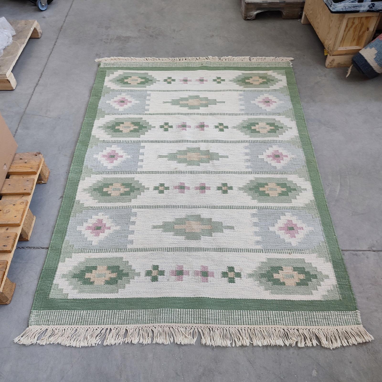 Kilim suédois vintage Rölakan motif géométrique, Suède 1980.
Véritable Röllakan en laine, tissé à la main, le champ vert clair est orné d'un motif géométrique composé de petites étoiles étagées dans des tons doux de rose, de beige et de vert. En