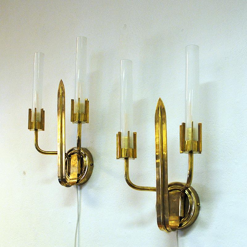 Pair of lovely brass wall sconces with a cylinder shaped lampshade of opaline glass on each side. Design: Swedish Grace. Produced in the 1940s. The inner stom has a sword design with bulb holders on the sides designed as a crown surrounding the
