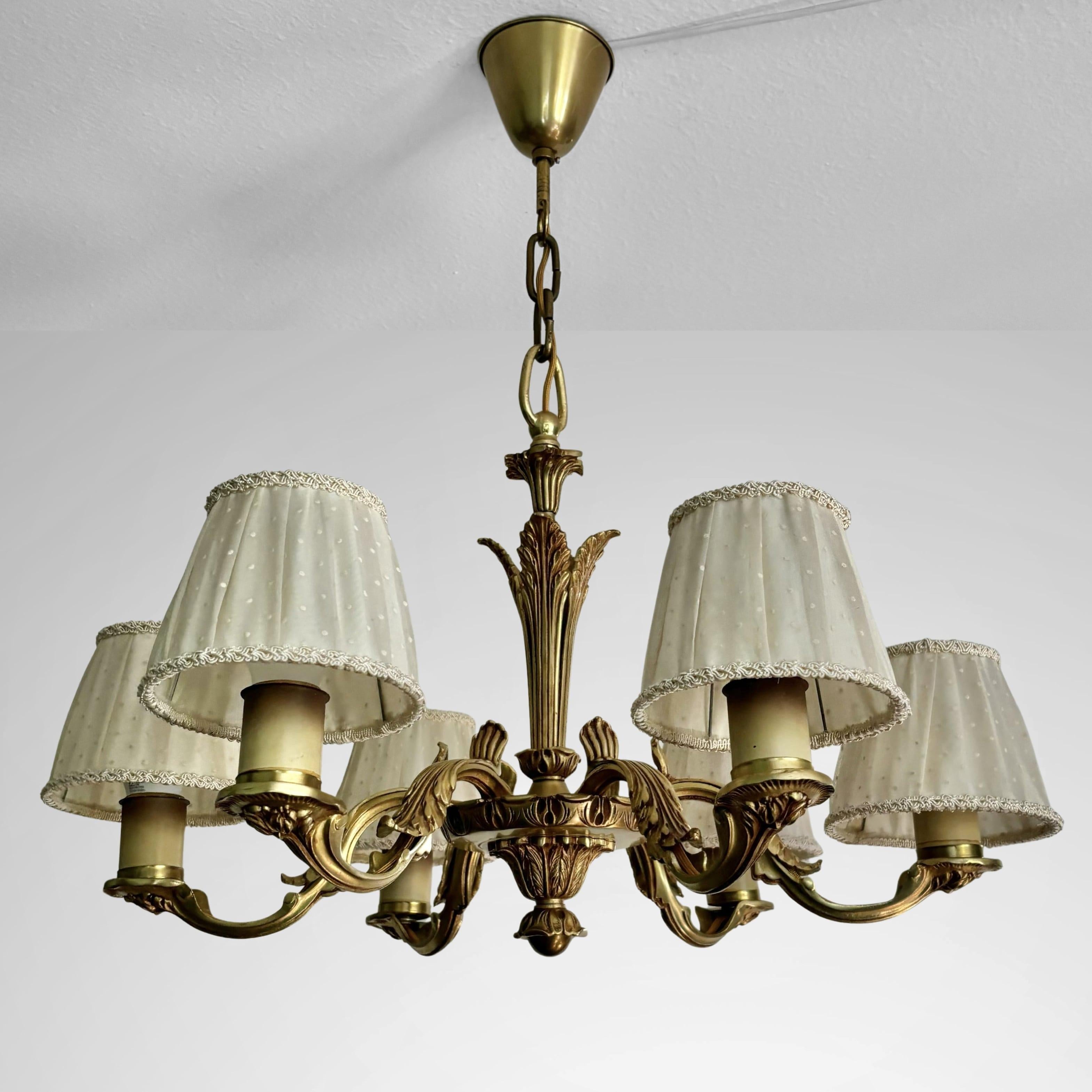 Un lampadario svedese a sei bracci degli anni '30, magistralmente realizzato in ottone massiccio e ornato da intricati motivi floreali e di foglie. Ogni braccio ospita un portalampada E27 a forma di candela, che completa perfettamente il fascino