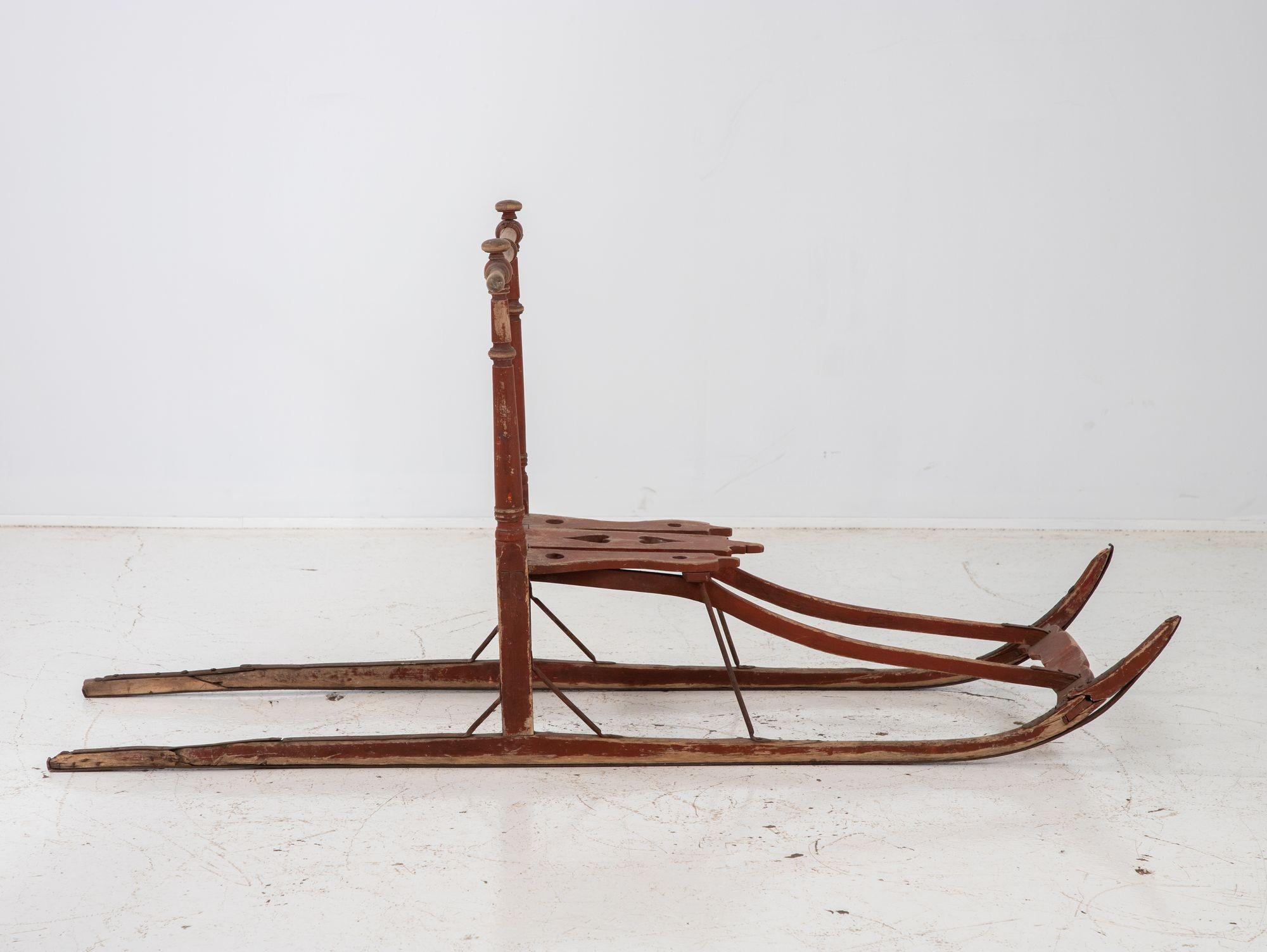 This antique Swedish kick sled is a charming piece of history, boasting a vibrant red frame that exudes a rustic allure. A delightful touch of folk art adorns the seat with a heart-shaped cutout, showcasing the intricate craftsmanship of the era.