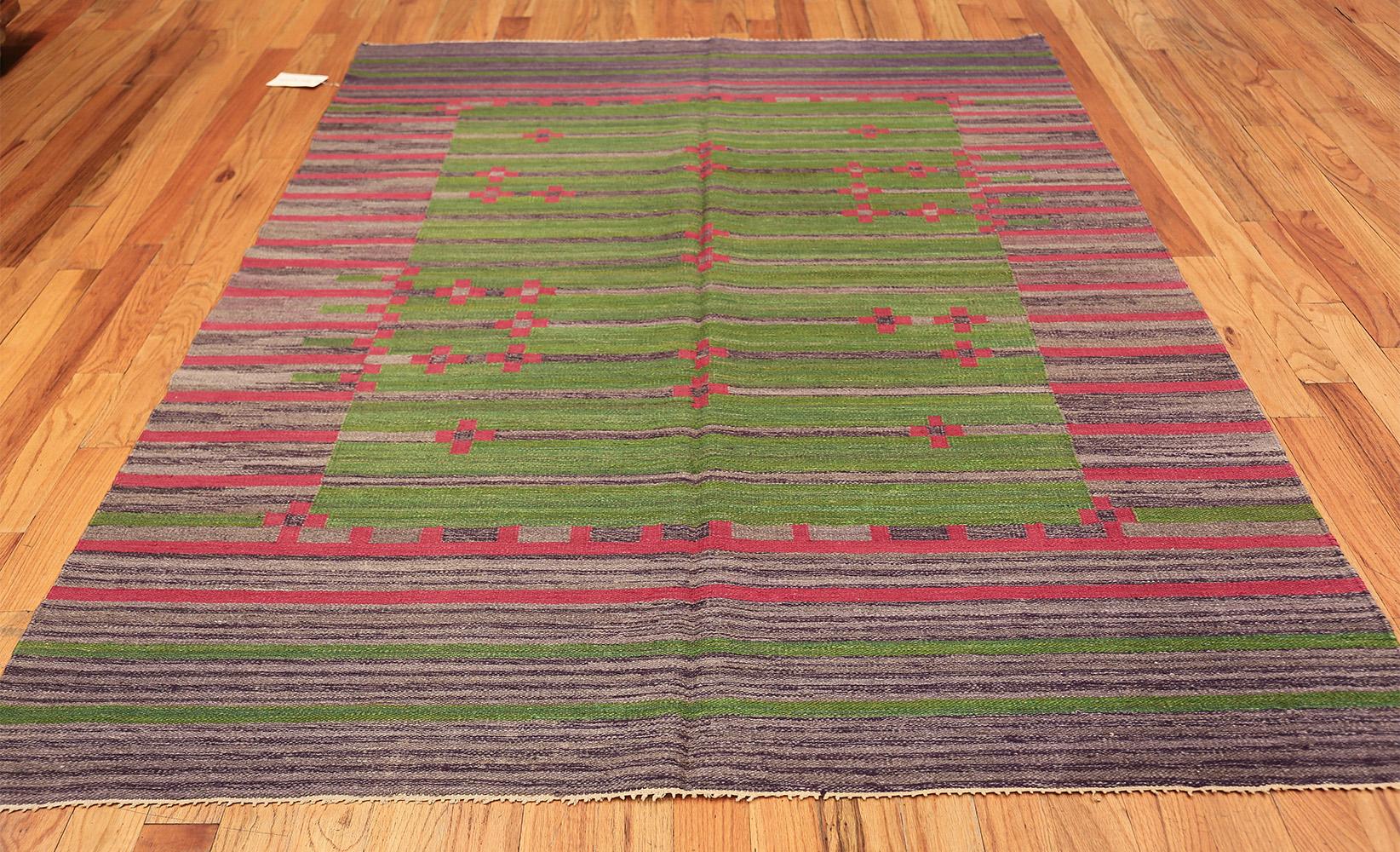 Boldly decorated and vividly colored, this evocative vintage Swedish Kilim features a stunning striated background that incorporates a rich variety of fuchsia pinks, violet hues and fresh green accents. The lively composition displays a cheerful,
