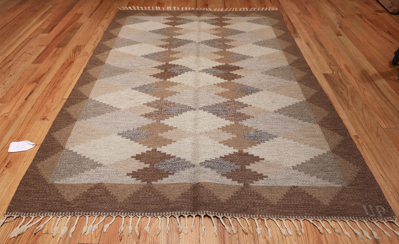 Drawn in a timeless, modern style, this outstanding signed Swedish Kilim features an artful pattern of reticulated lozenges and quarter-rhombus motifs that have an earthy masculine countenance. The beautifully decorated field showcases an exquisite