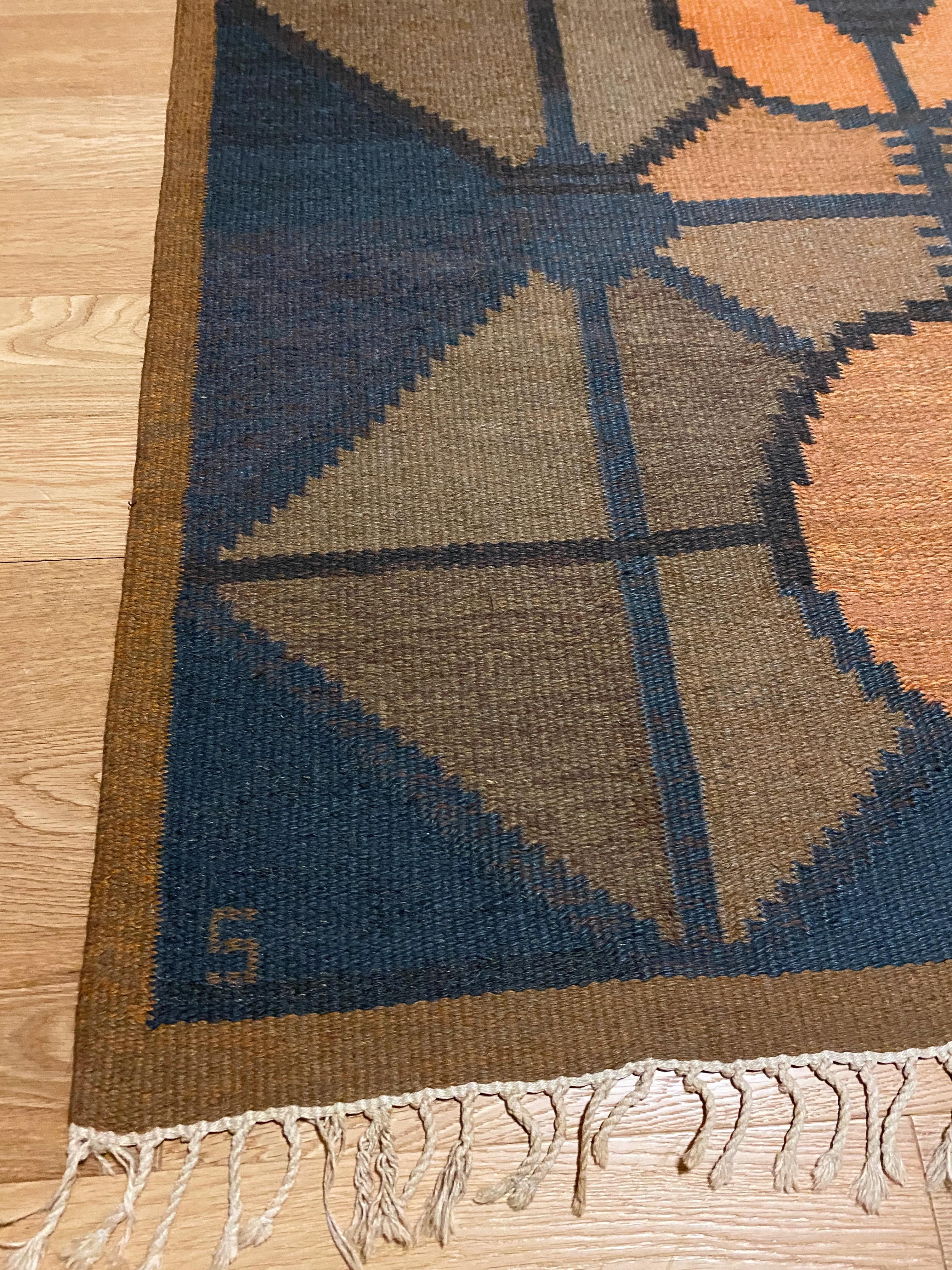 Beautiful Vintage Swedish Kilim rug by Brita Svefors. Geomatric shapes in burnt orange, blue and brown shades creates a stunning design. Age appropriate wear with teared fringes and small repairs. But overall nothing that impacts the great design of