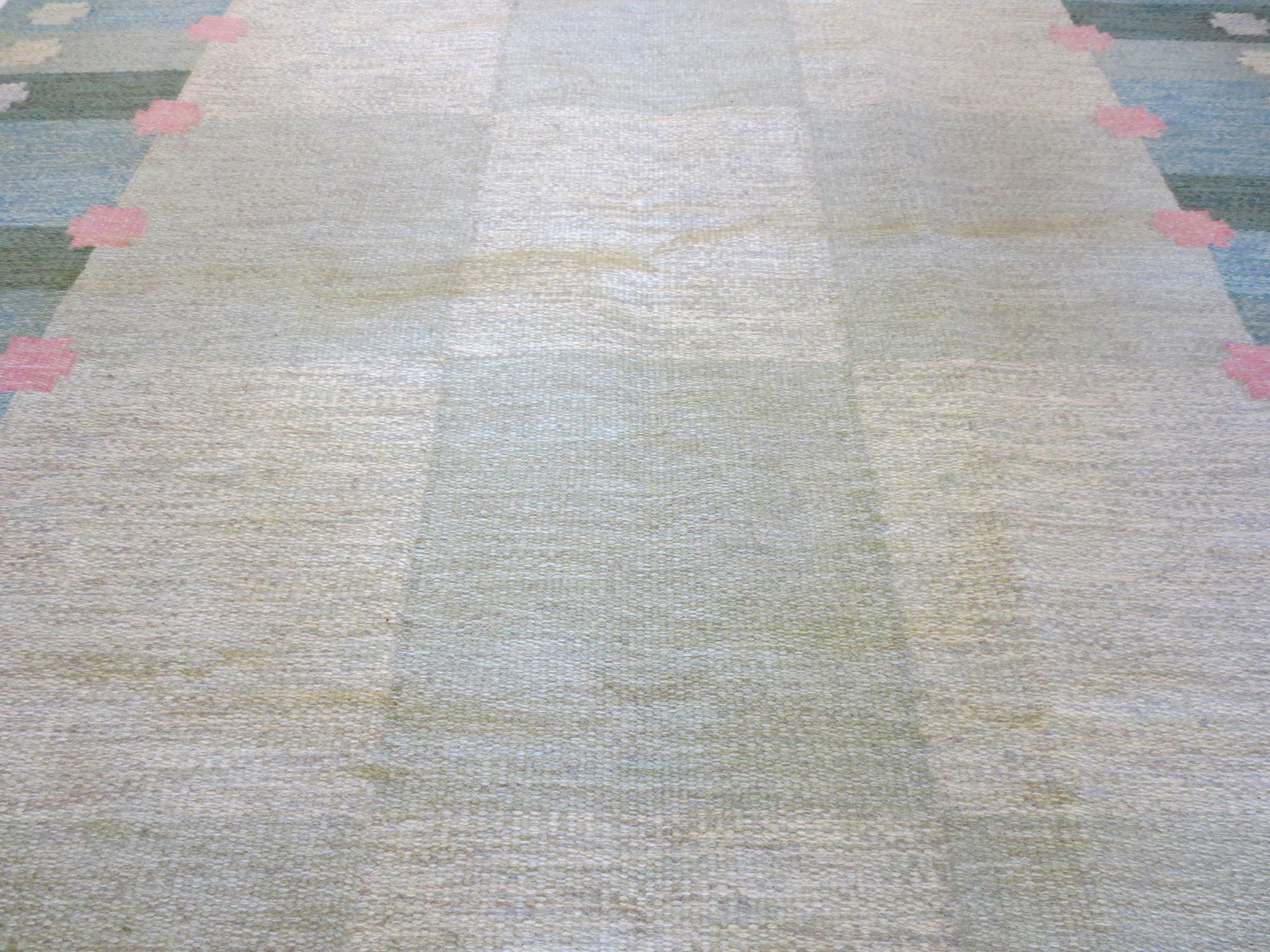 Il s'agit d'un magnifique tapis Kilim suédois vintage de la designer Anna Joanna Angstrom datant du milieu du 20e siècle. Ses couleurs douces de verts, de bleus et de roses évoquent un sentiment de calme tandis que les éléments verticaux et
