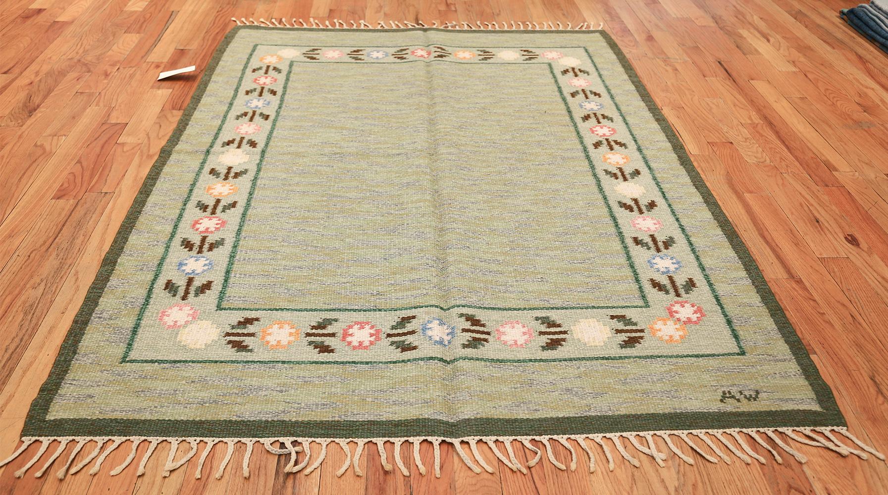 Vintage Swedish rug, origin: Swedish. Size: 5 ft. 5 in x 8 ft. (1.65 m x 2.44 m)

This vintage signed Kilim showcases a wonderful and understated collection of floral motifs and flat-weave figures that embody the soft, sophisticated style of