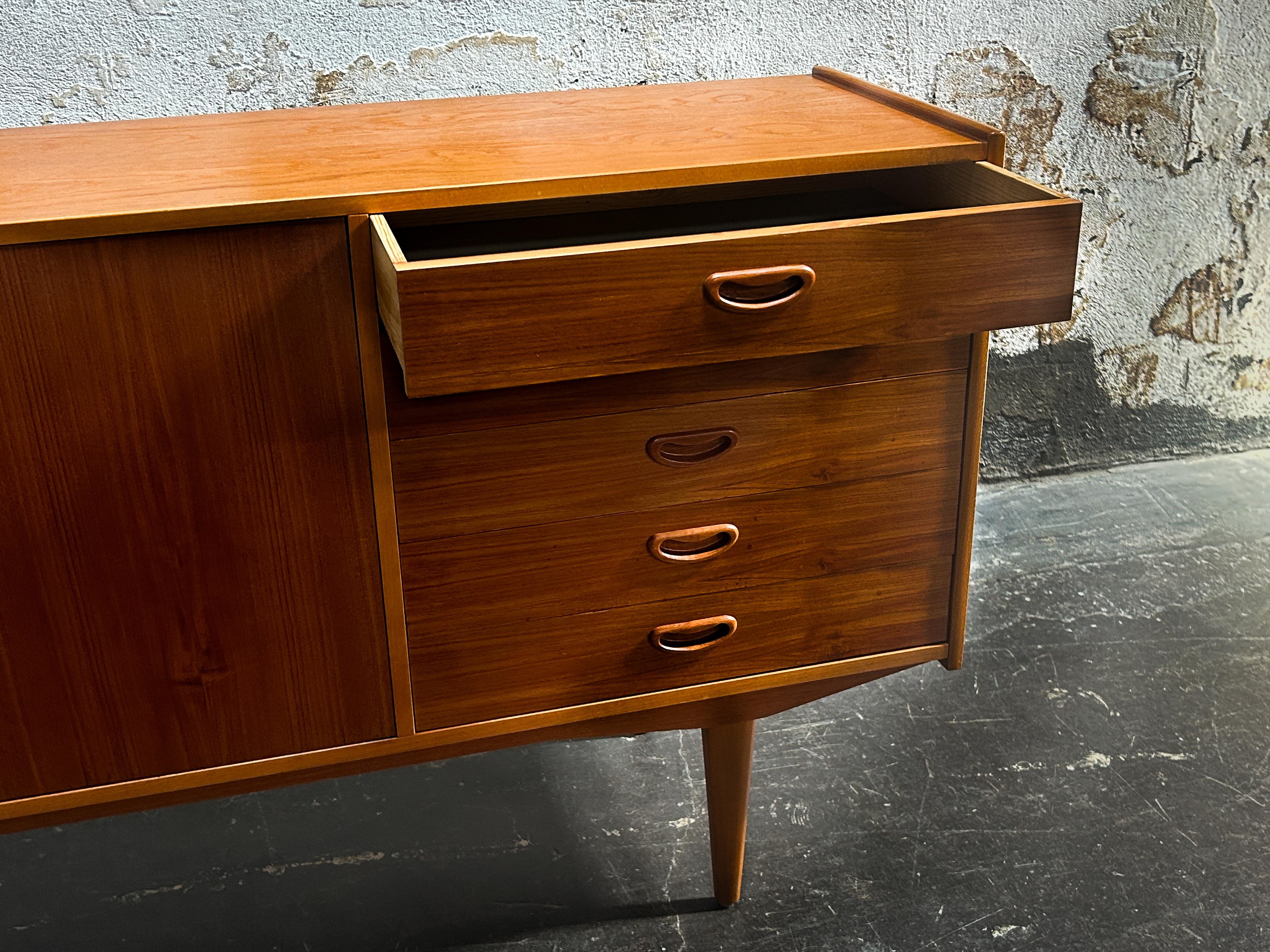 Vintage Mid-Century Modern credenza in rich book-matched teak. Attributed to SMI Sveriges Möbelindustriförbund and made in Sweden circa 1960.  This handsome rich teak cabinet has two sliding doors and four drawers with sculpted recessed pulls.  In