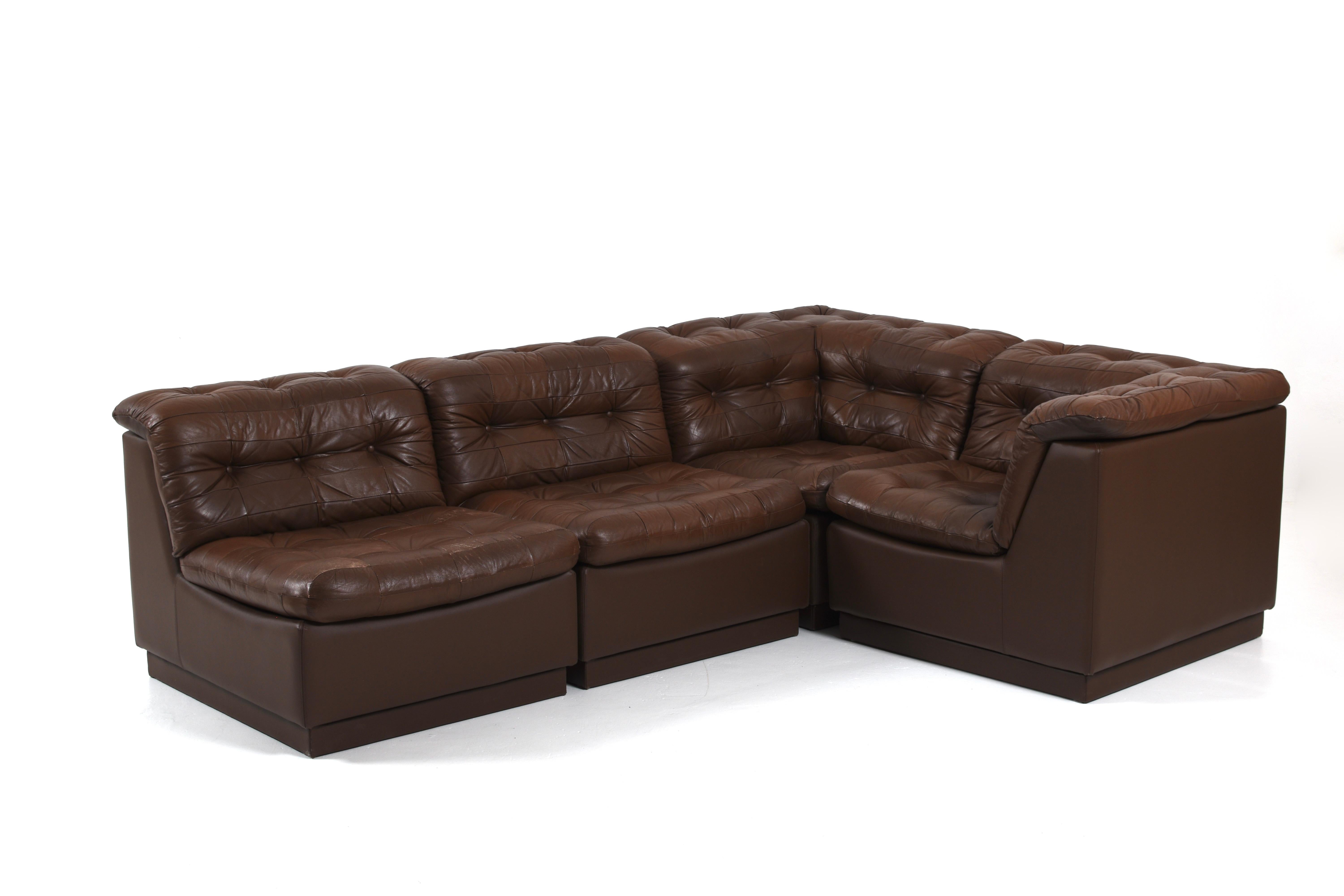 A striking Swedish modular leather sofa from the 1970s, offering both sculptural form and exceptional comfort. Upholstered in supple chocolate brown leather with signature deep tufting and generous padding, this four-piece configuration includes two