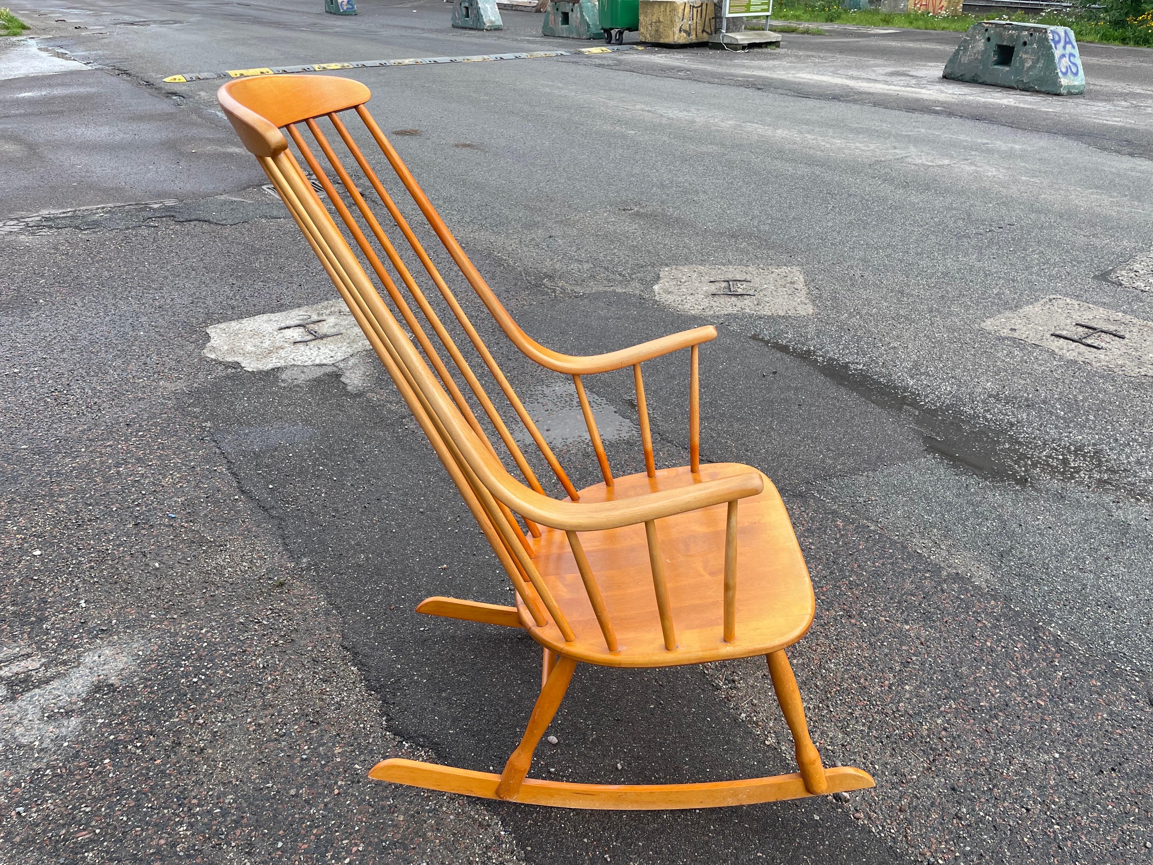 Ce rocking-chair Grandessa a été conçu par Lena Larsson pour la manufacture suédoise Nesto dans les années 1960. Le fauteuil est fabriqué en bois de hêtre.  Le dossier haut se transforme en accoudoirs. La structure est conçue pour assurer un