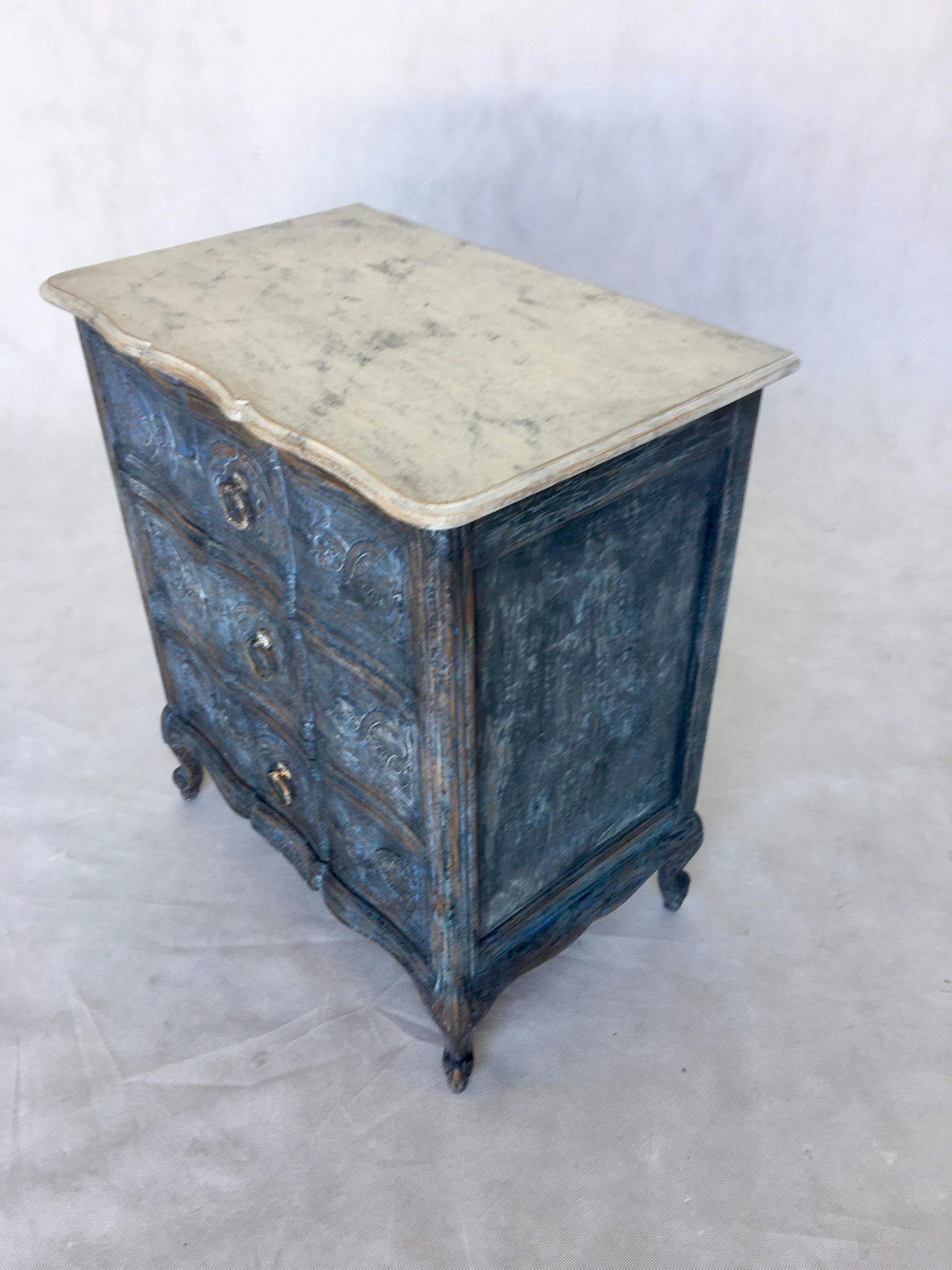 This Swedish Rococo style dresser features embellished drawers in dark blue. The top of the dresser is painted marble.
  