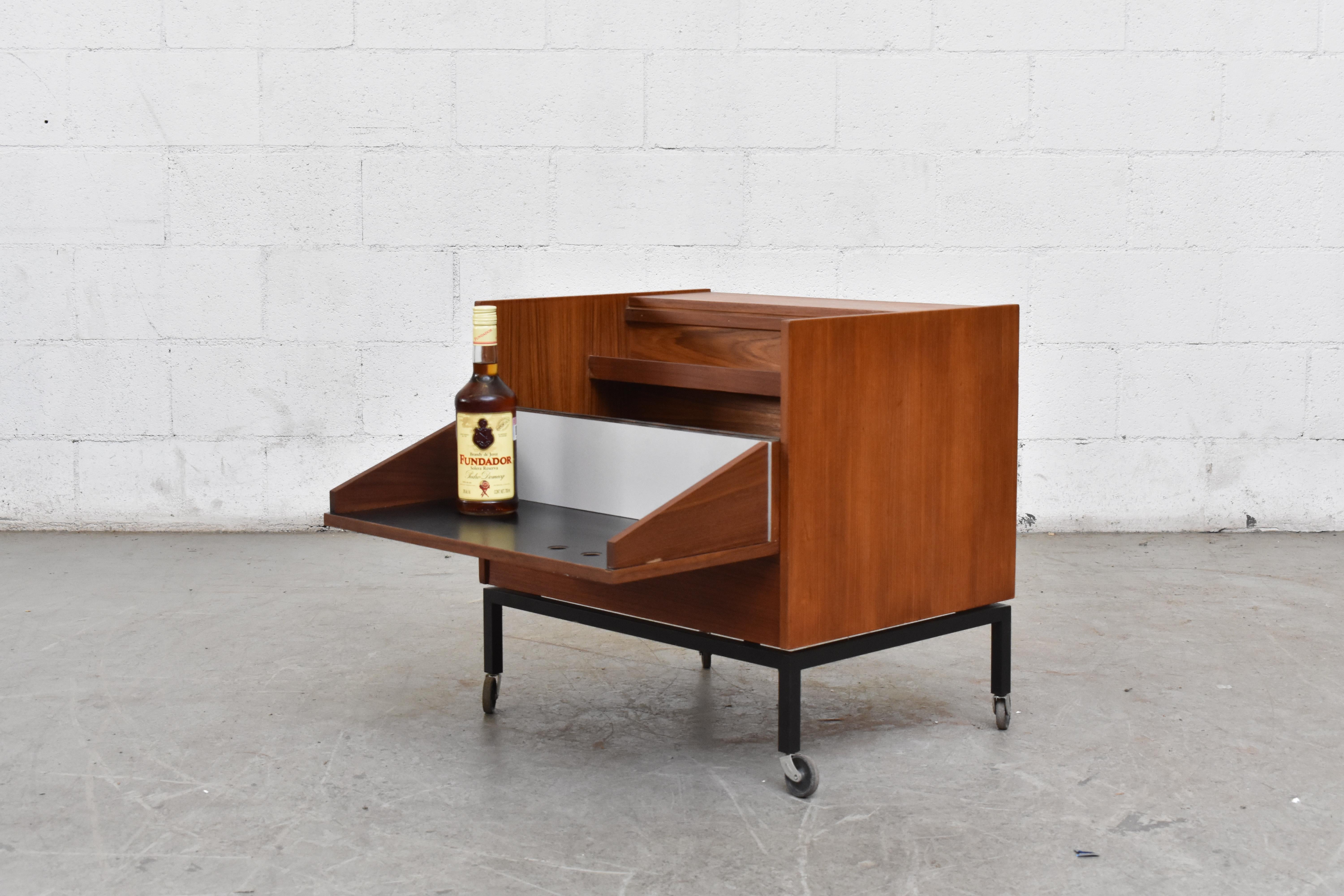 Swedish trolley bar. Lightly refinished teak body with black formica exterior. Teak and white formica interior. Both sides open to reveal interior bar storage for glasses, bottles, etc. Black enamelled metal frame with rolling caster wheels.