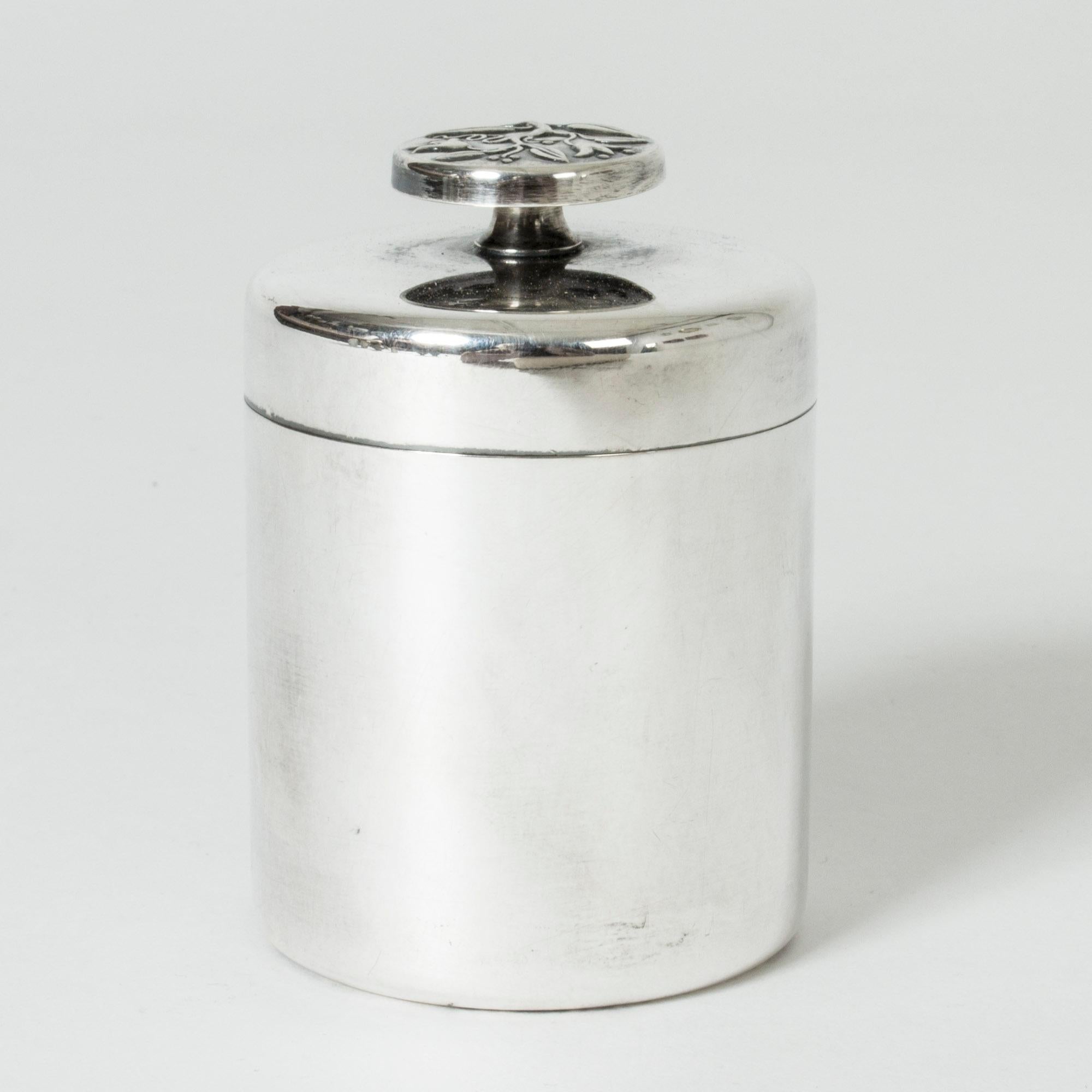 Sleek silver jar from GAB, with a beautiful flower decor on the knob. Art Nouveau inspired decoration subtly embossed on the flat, spherical knob.