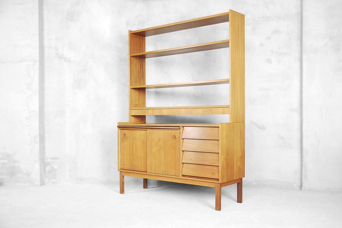 This Mid-Century Modern bookcase was manufactured in Sweden during the 1960s. It has been finished in teak. This unit consists of two parts: sideboard and detachable bookshelf. The sideboard has a two sliding doors, four drawers and pullout desk