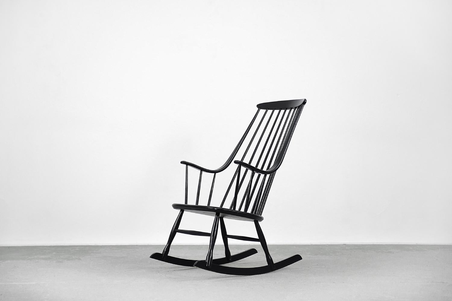 This Grandessa rocking chair was designed by Lena Larsson for the Swedish Nesto manufacture during the 1960s. The armchair is made of beech wood. It has been finished with black varnish. The high backrest seamlessly transforms into the armrests. The