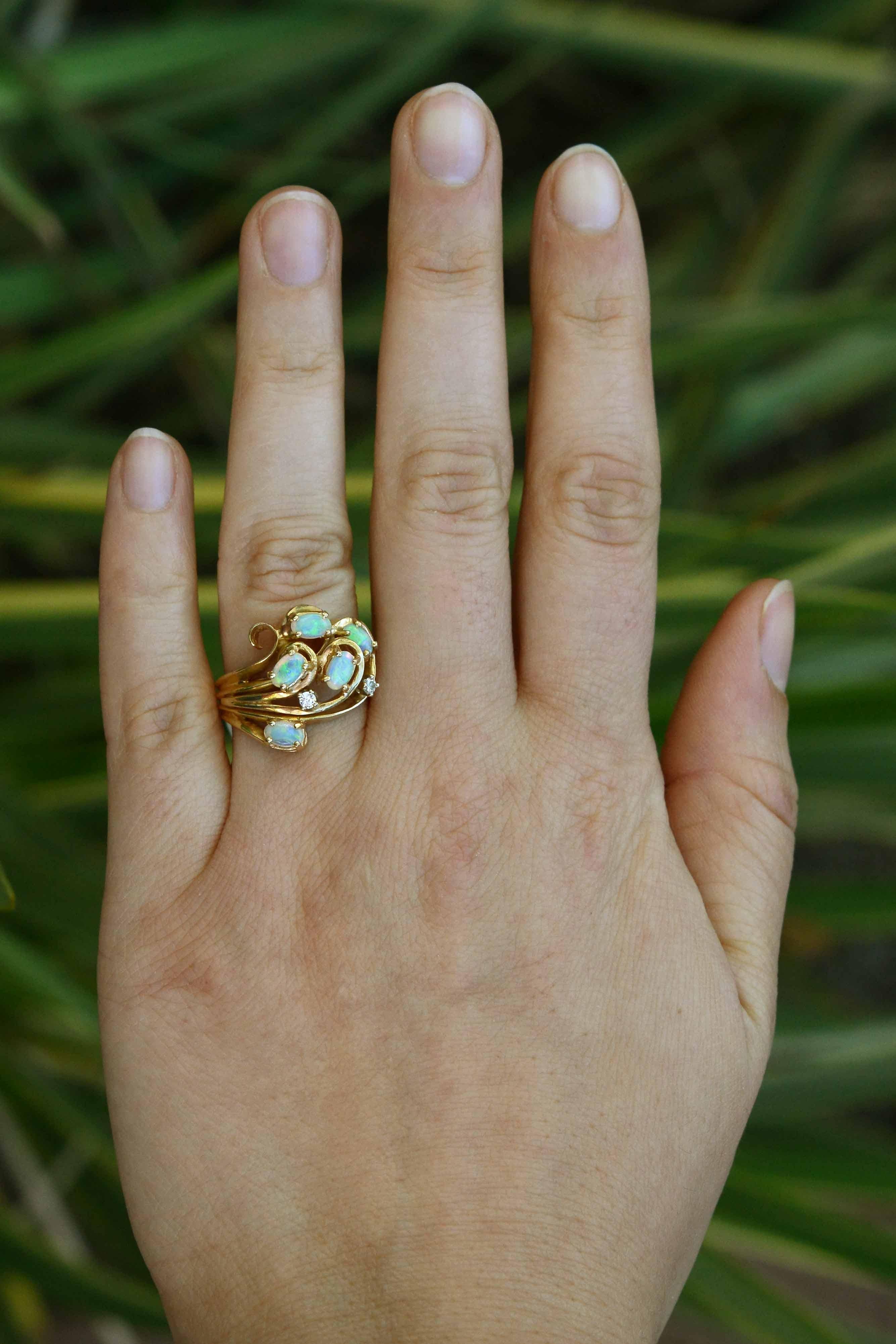 A graceful, flowing ring with swirling 14k yellow gold and blazing crystal brush-stroke opals that flash an incredible blue, green, and orange array. Studded with dainty diamonds that add a beautiful sparkle. This unique, vintage 1960s cocktail ring