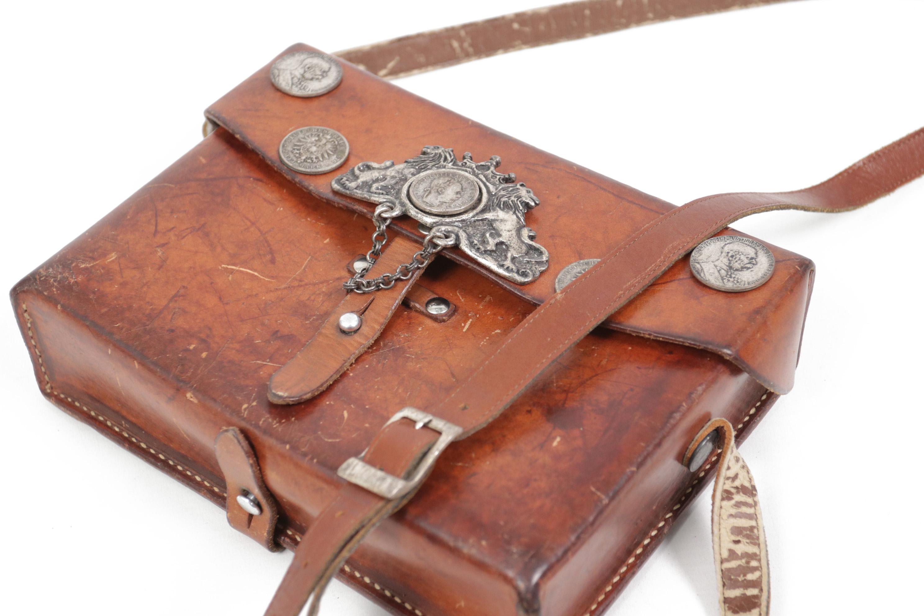 Super cool leather bag, used in the Swiss army.
This item is covered with casts of German coins which probably happened later, it makes this bag really unique.
The leather of the bag has a beautiful patina.
The shoulder strap has damage on the