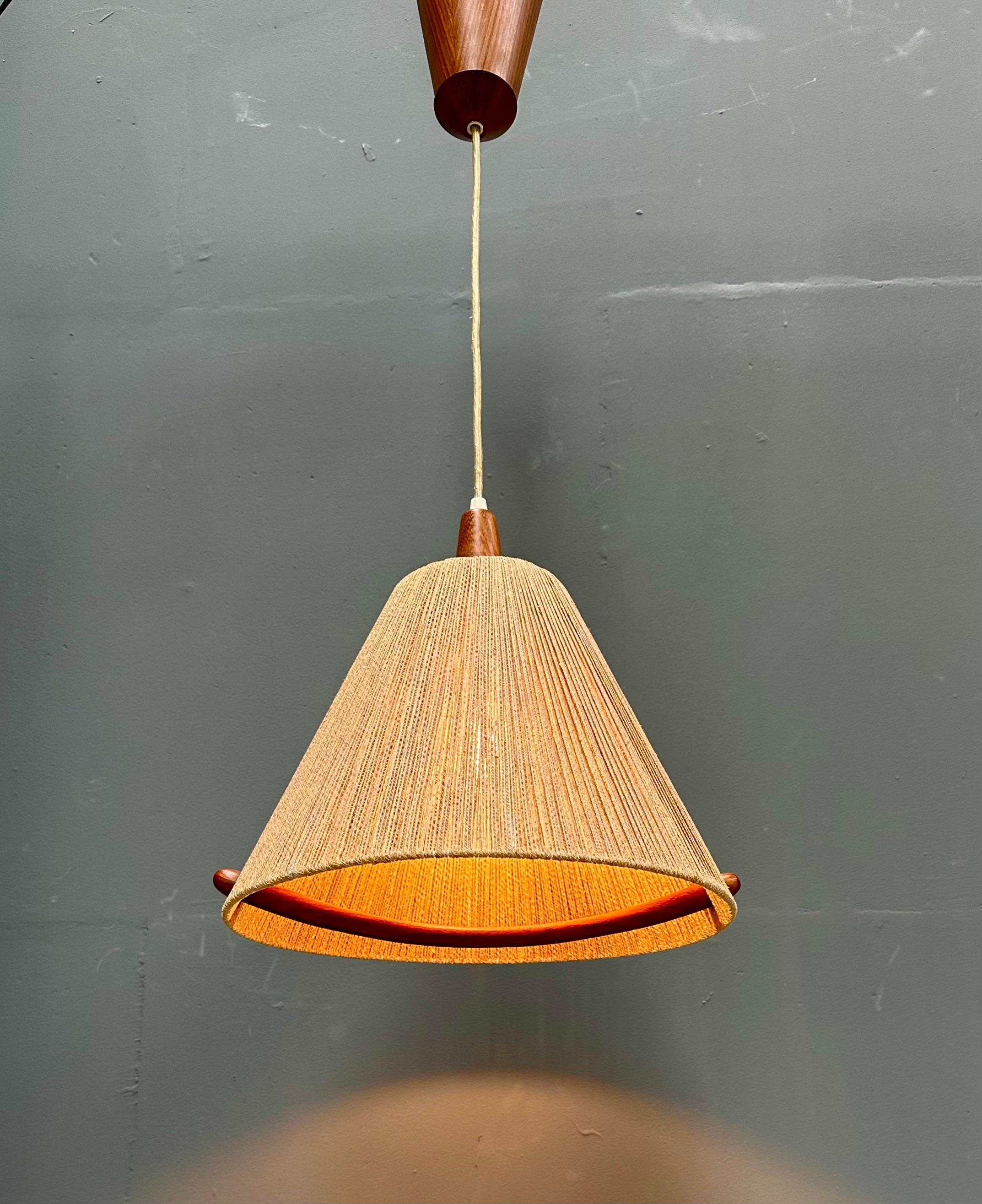 A vintage Swiss extensible hanging lamp made of teak and sisal. Designed and manufactured in Switzerland by Temde Leuchten in the seventies . The sisal lampshade in combination with a E27 (US E26) light bulb creates a beautyfull warm and pleasant