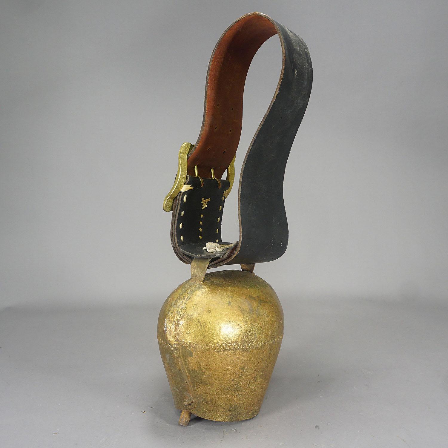 A large handforged and gilded iron cow bell from the Swiss alps manufactured around 1920. The bell comes with its black leather strap with buckle (most probably later replaced). These bells are used to locate cattles in the pasture. Cows wear them