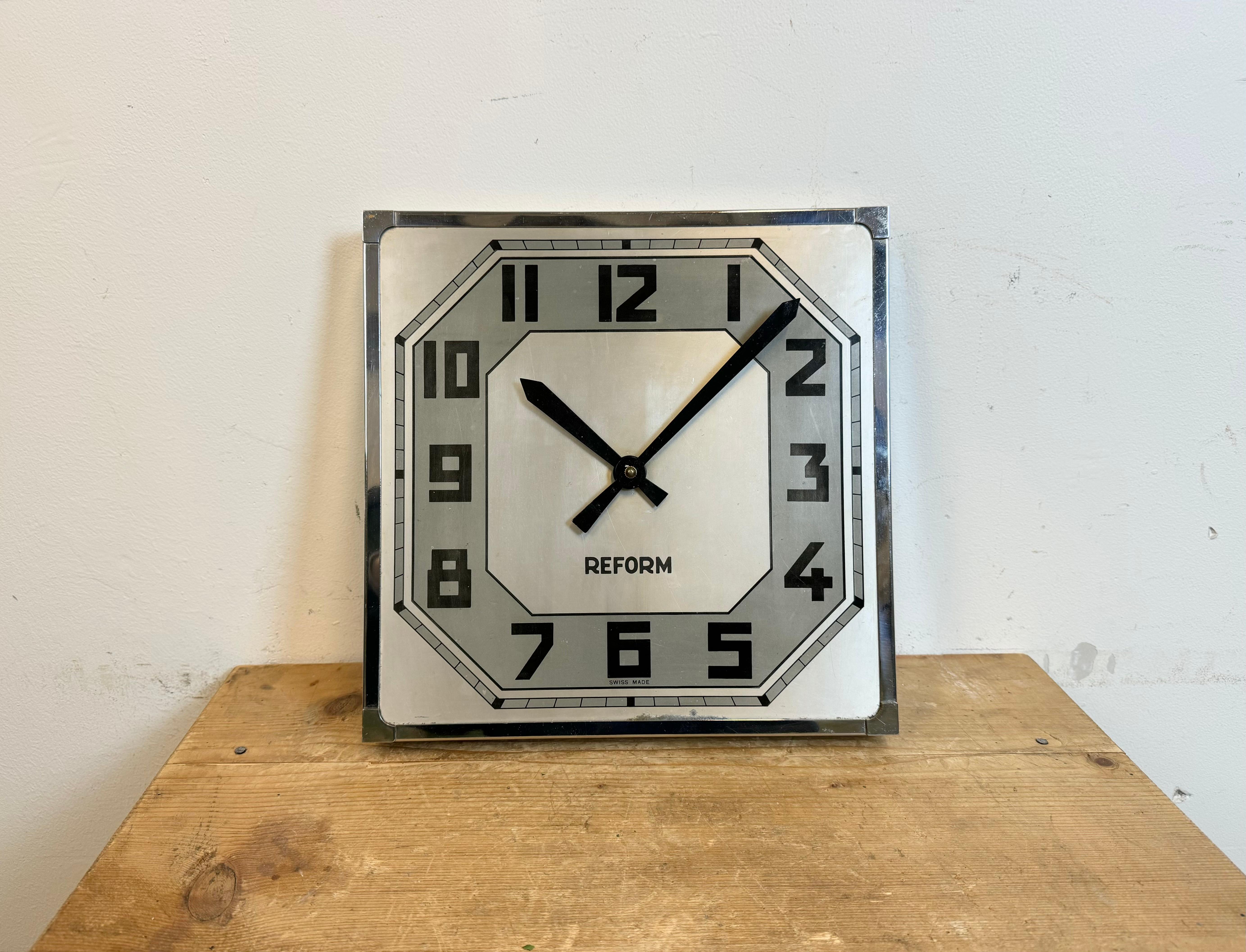 Horloge murale industrielle vintage fabriquée par Reform en Suisse dans les années 1950. Elle se compose d'un cadre carré en fer chromé, d'un cadran en métal et d'aiguilles en aluminium. Le mouvement original nécessite un 3R12  Batterie de 4,5V.
La