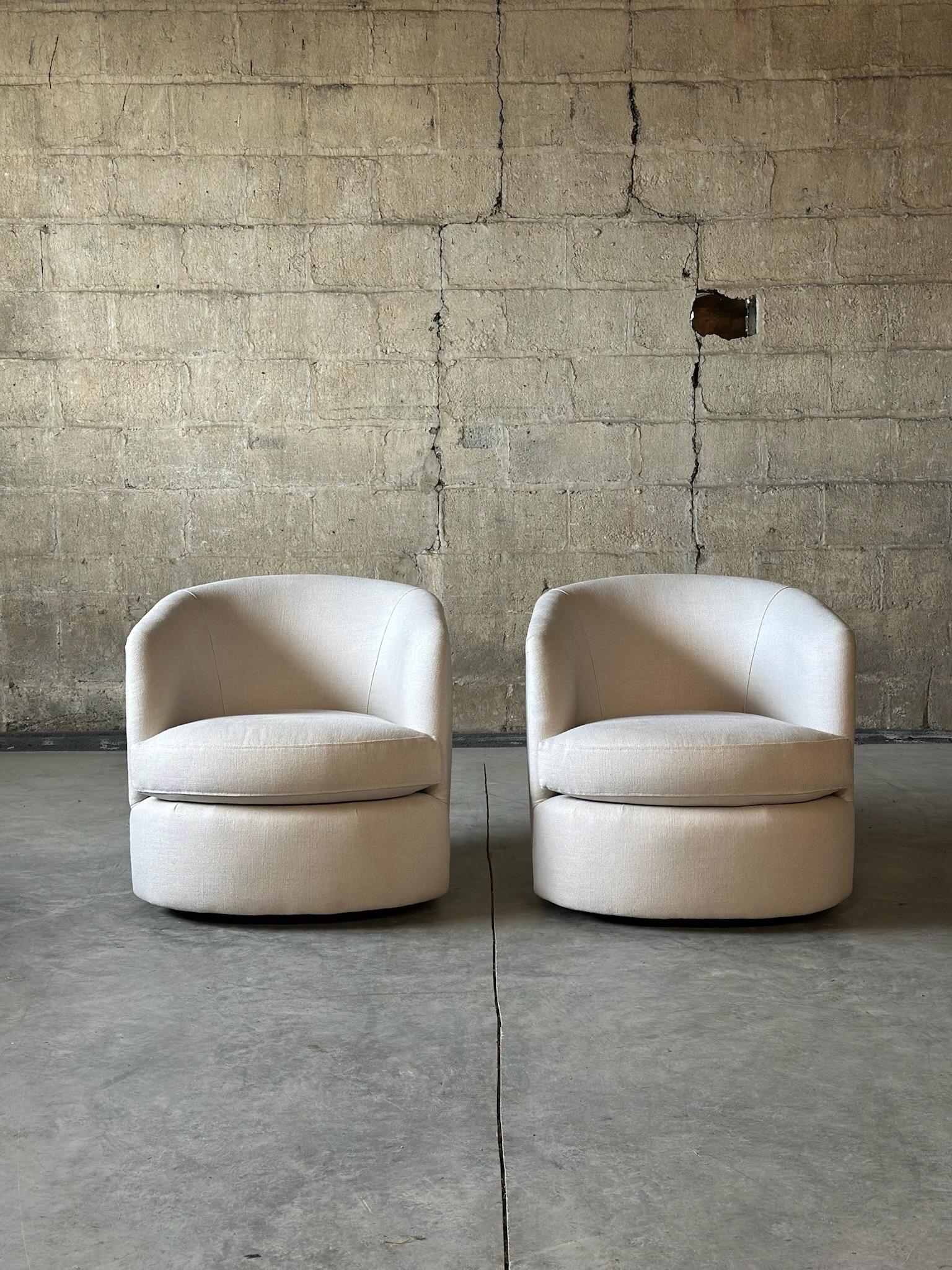A beautiful pair of swivel bucket chairs in a Schumacher cream linen. Recently reupholstered and comfortable. Clean lines and timeless design makes them a great pick.