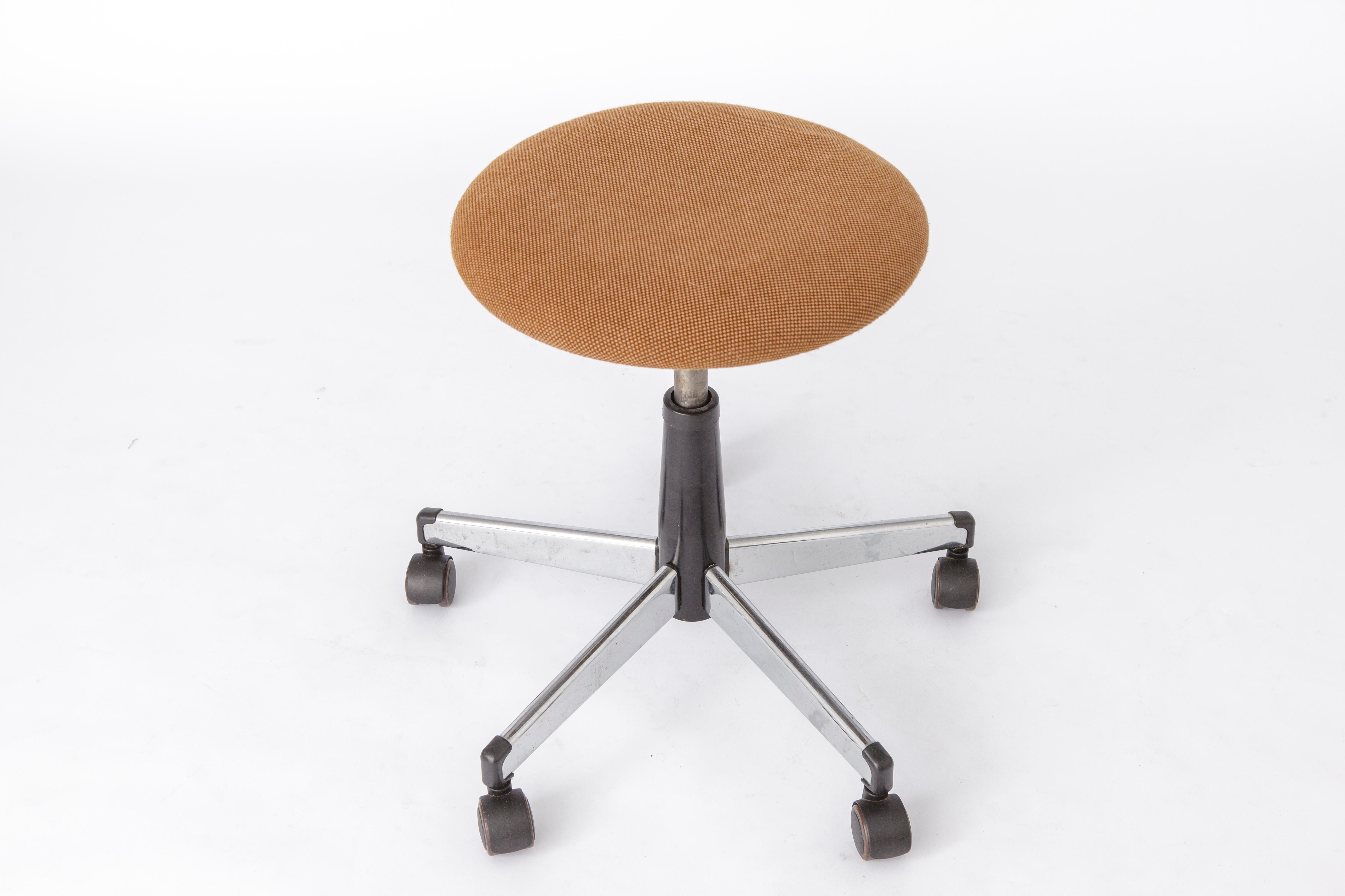 Adjustable vintage stool from the 1960s. 
Manufacturer: Martin Stoll GmbH, Germany. 

Metal frame and wooden seat. Covered with brown textile. Original cover.
Good condition, the adjustment mechanism works perfectly.