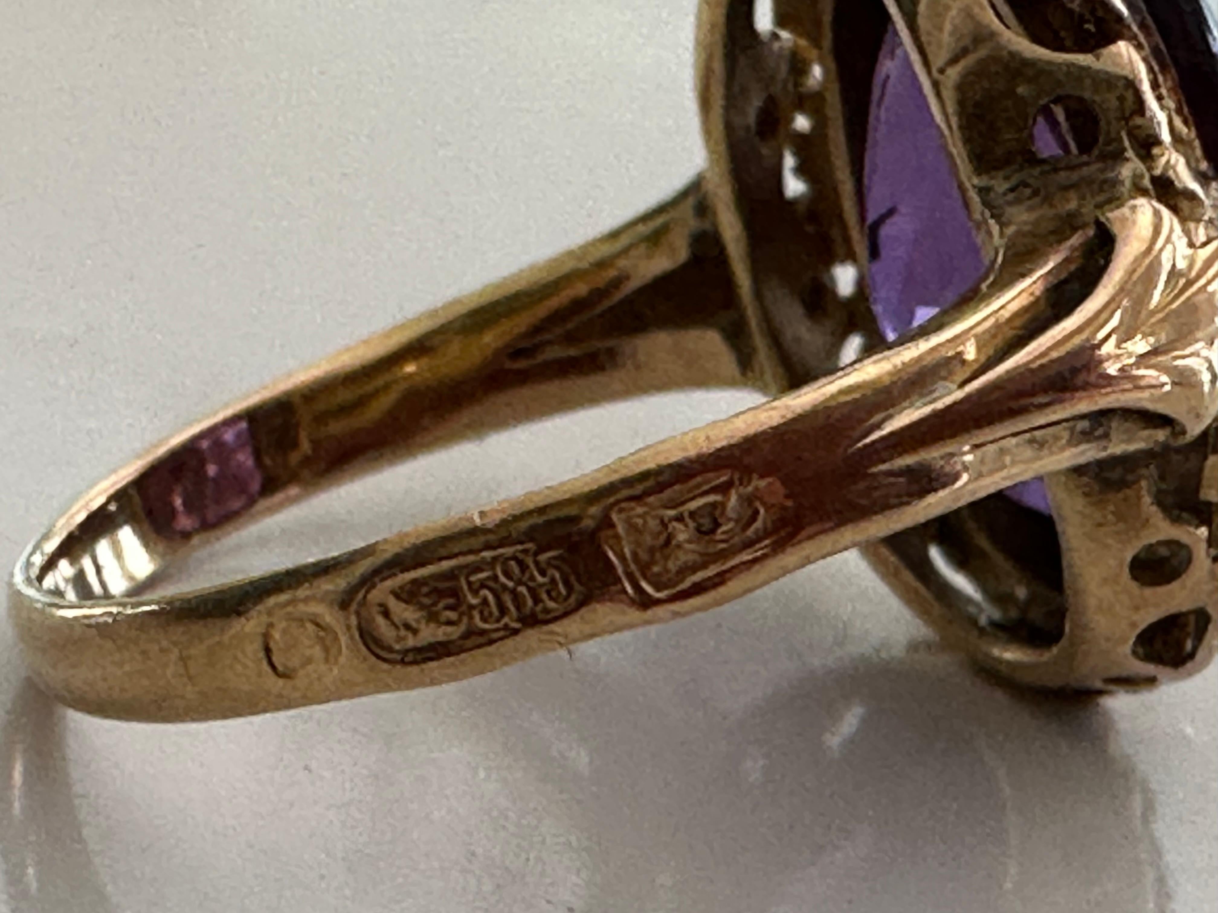 An oval shaped synthetic purple sapphire measuring 10 x 15mm radiates from within a hand carved band fashioned from 14kt yellow gold. The European marks on the outside of the band indicate the ring was most likely manufactured in England. 


