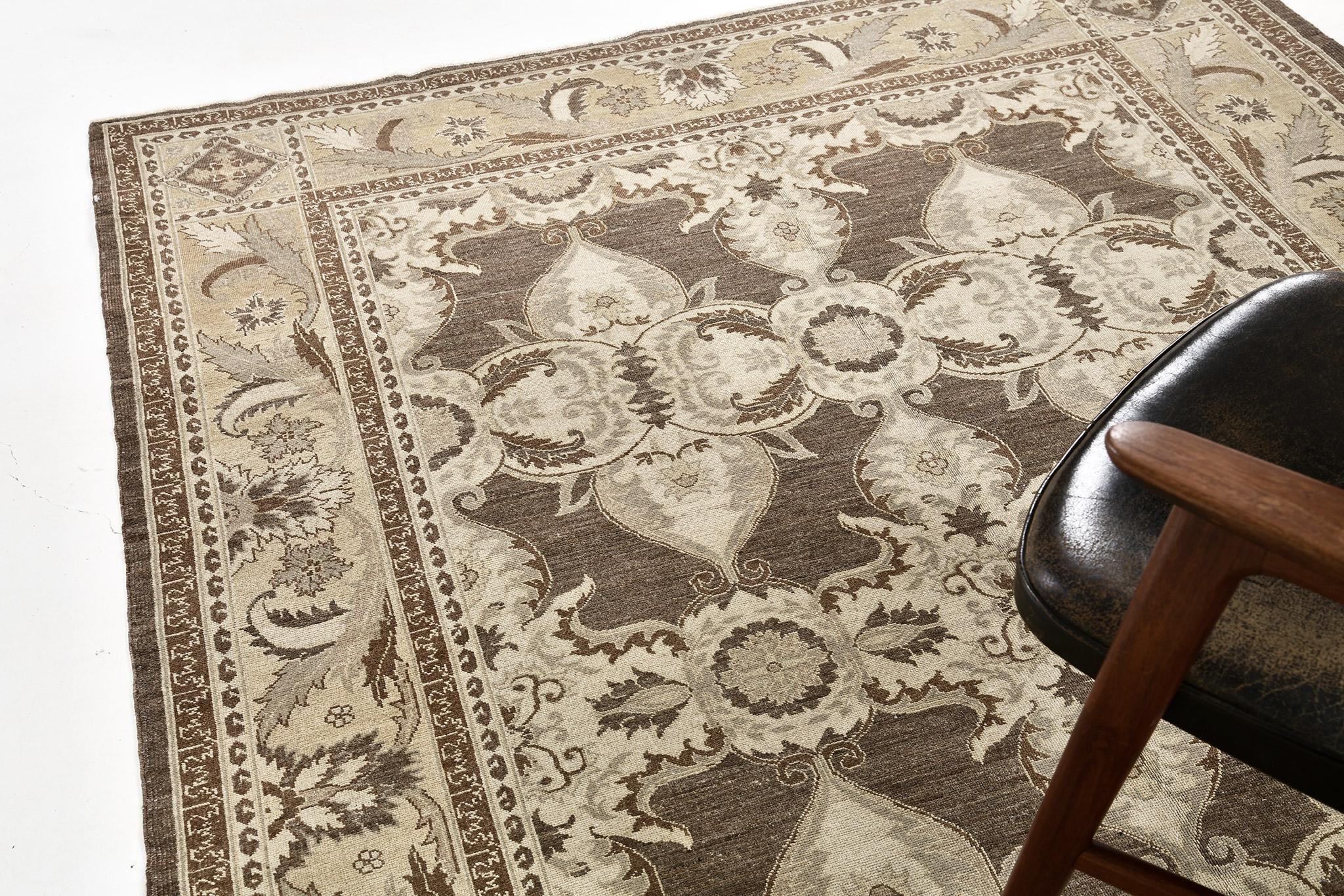 An astounding revival of Arts and Craft Style rug that features the elegant tones of sand, ivory, and coffee. Laying gracefully in a solid-colored field, the blooming palmettes and ornate botanical patterns are formed symmetrically enclosed by