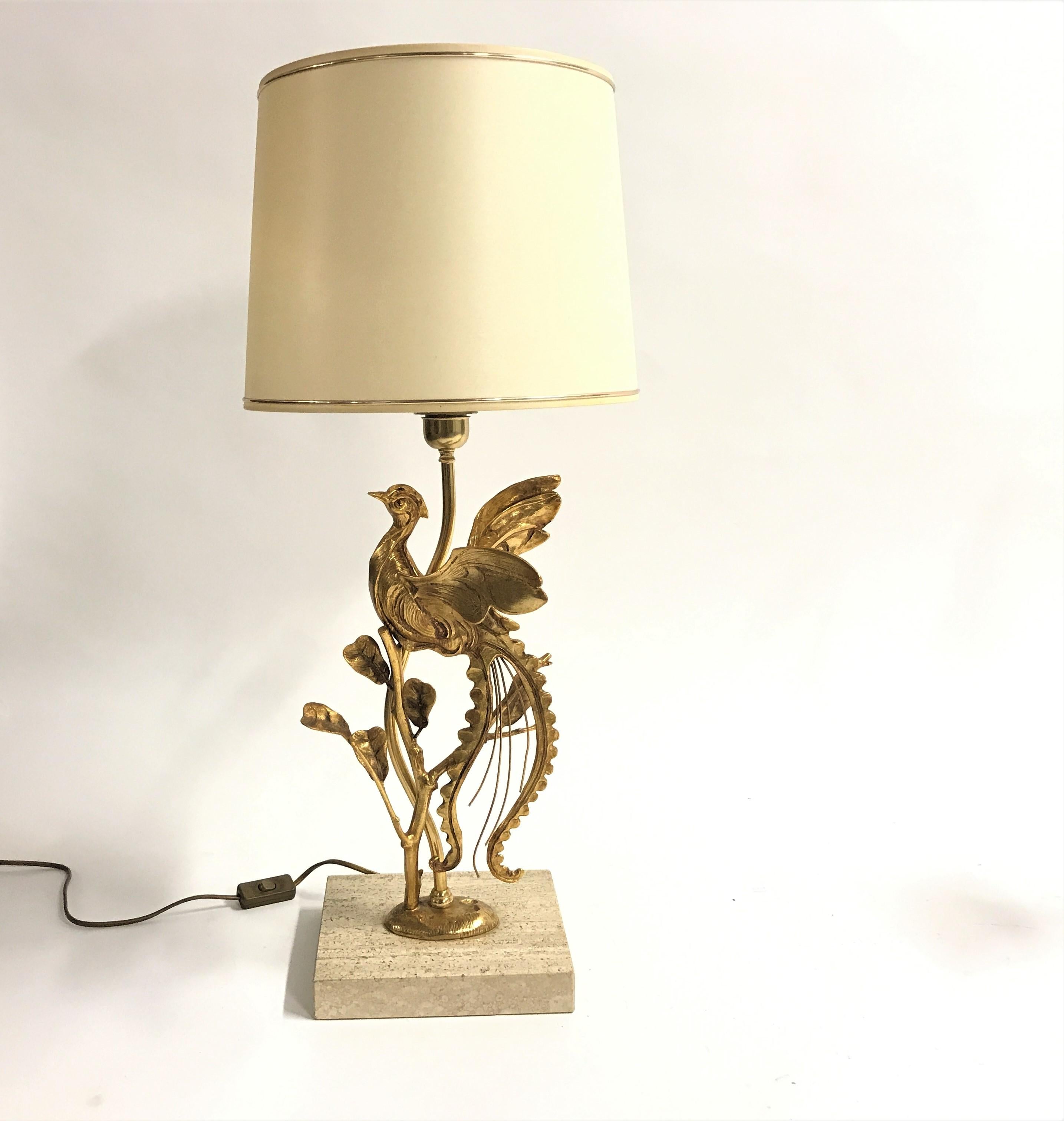 Vintage natural table lamp depicting a peacock on a branch with leaves.

The brass sculpture is mounted on a travertine stone base, which is typical for Italian lamps.

This lamp is a perfect fit in modern day interiors to add a touch of