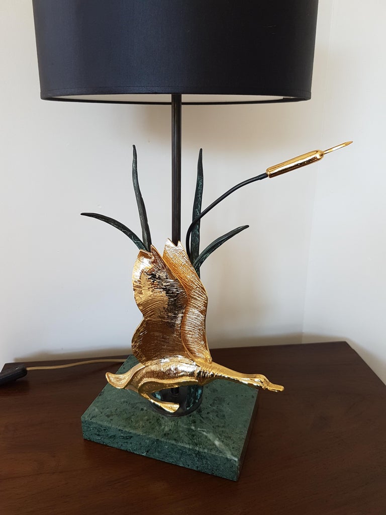 Vintage natural table lamp depicting a bird that's flying away.

The brass sculpture is mounted on a green marble stone base.

This lamp is a perfect fit in modern day interiors to add a touch of Hollywood Regency in your home.

It comes with