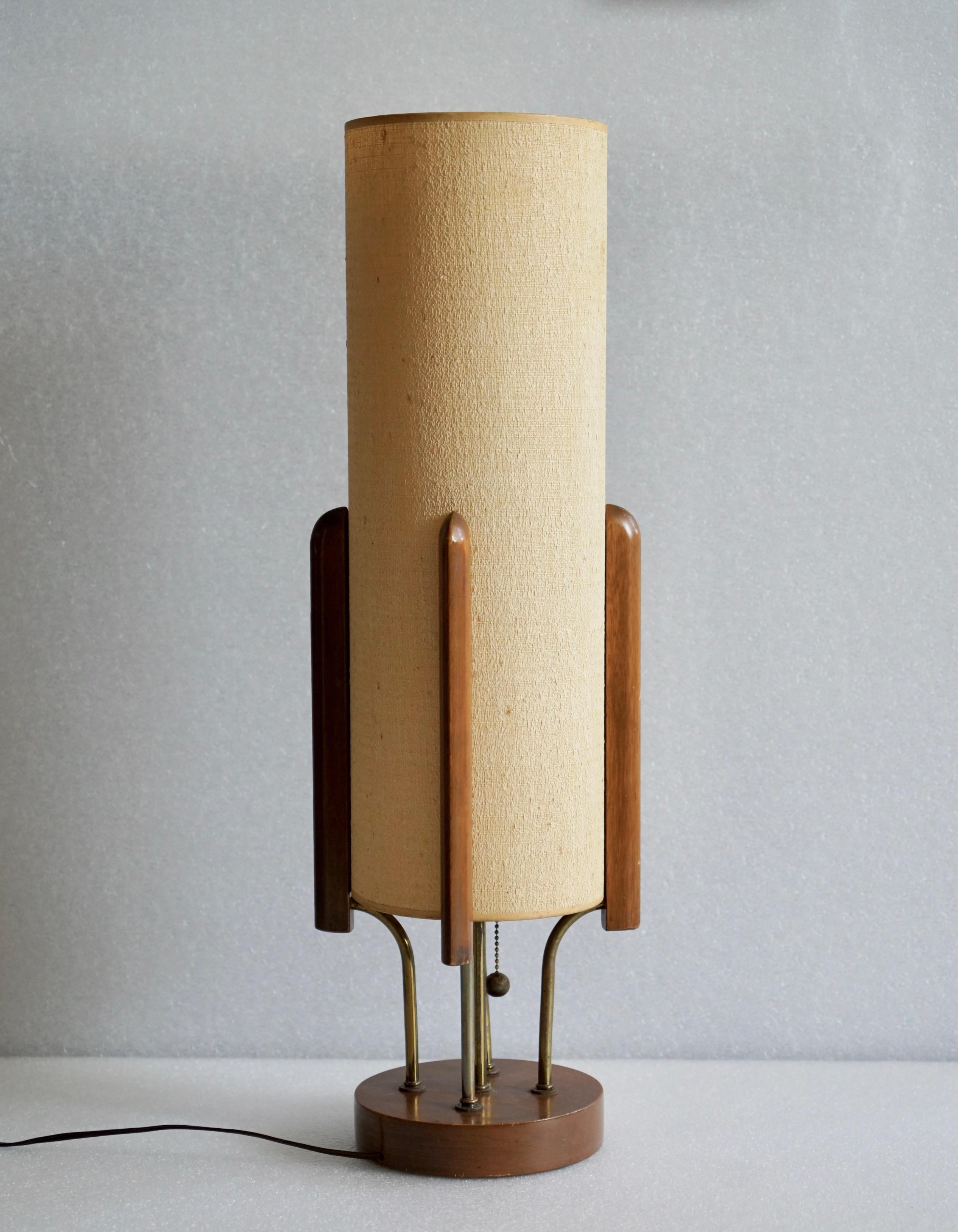 Une lampe de table vraisemblablement produite par Modeline Lamp Co. 
USA, Ciarca 1960th.
Base en teck et laiton avec abat-jour en tissu sur papier.
Abat-jour et fils d'origine. La lampe est en état de marche.