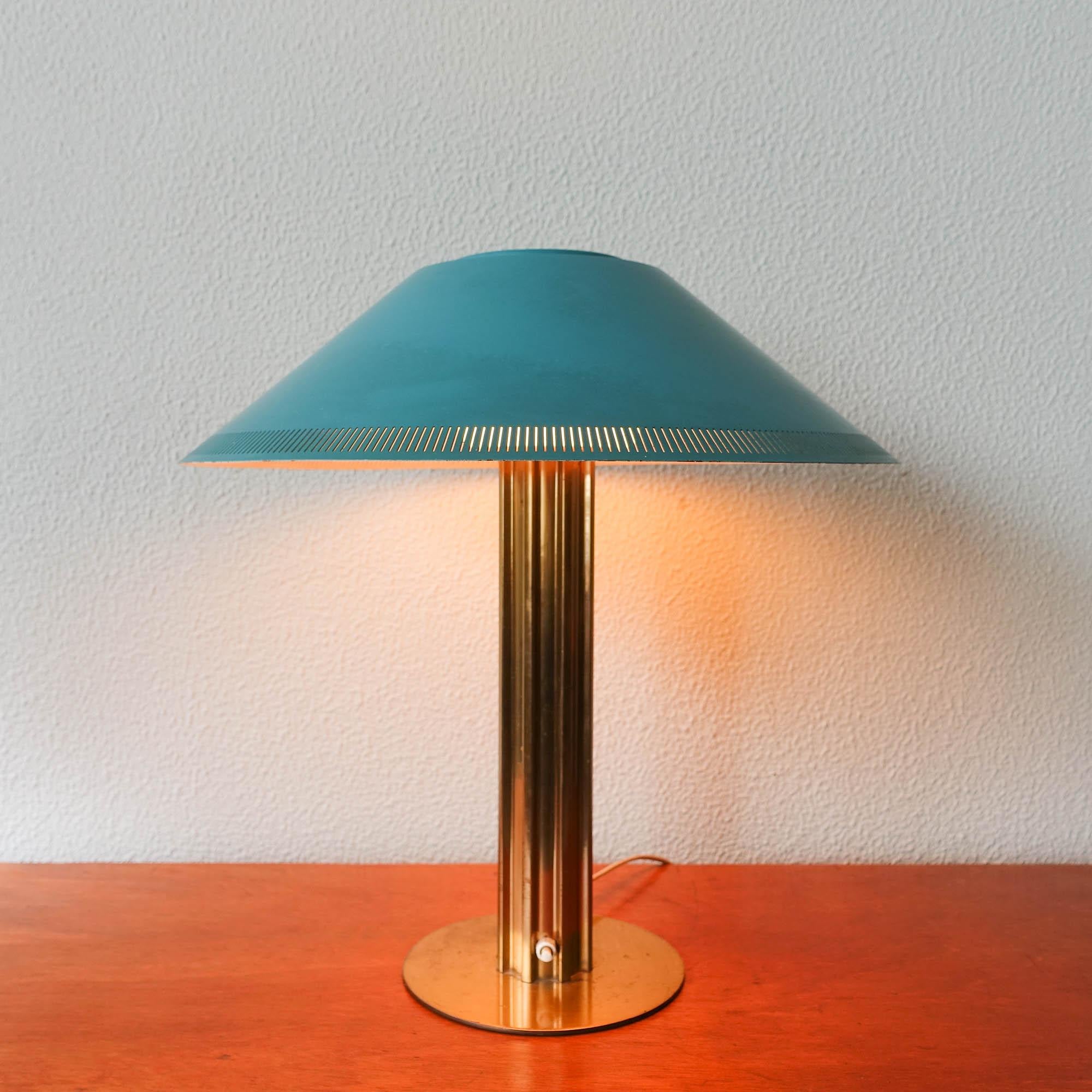 This table lamp was designed by Bent Karlby and produced by Lyfa, in Denmark, during the 1950's. It features a ribbed brass base, on top of wich is an opaline white glass, where a green metal lampshade is set. In original and good vintage condition.